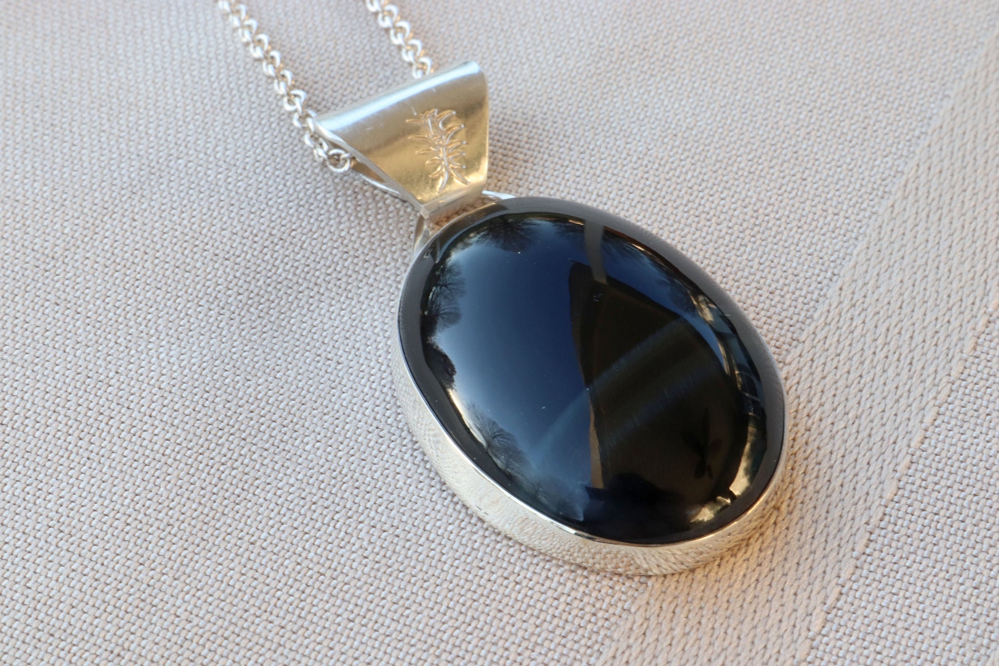 A rare African Blue Tiger's Eye gemstone handcut and polished in our Missouri studio. This one-of-a-kind gem is meticulously fashioned in Argentium 935 Silver  The African Blue Tiger's Eye cabochon with unique coloring and blue striped patterns, making this piece one-of-a-kind. The materials used are eco-friendly and nature-friendly; Argentium Silver is made from 100% recycled silver.