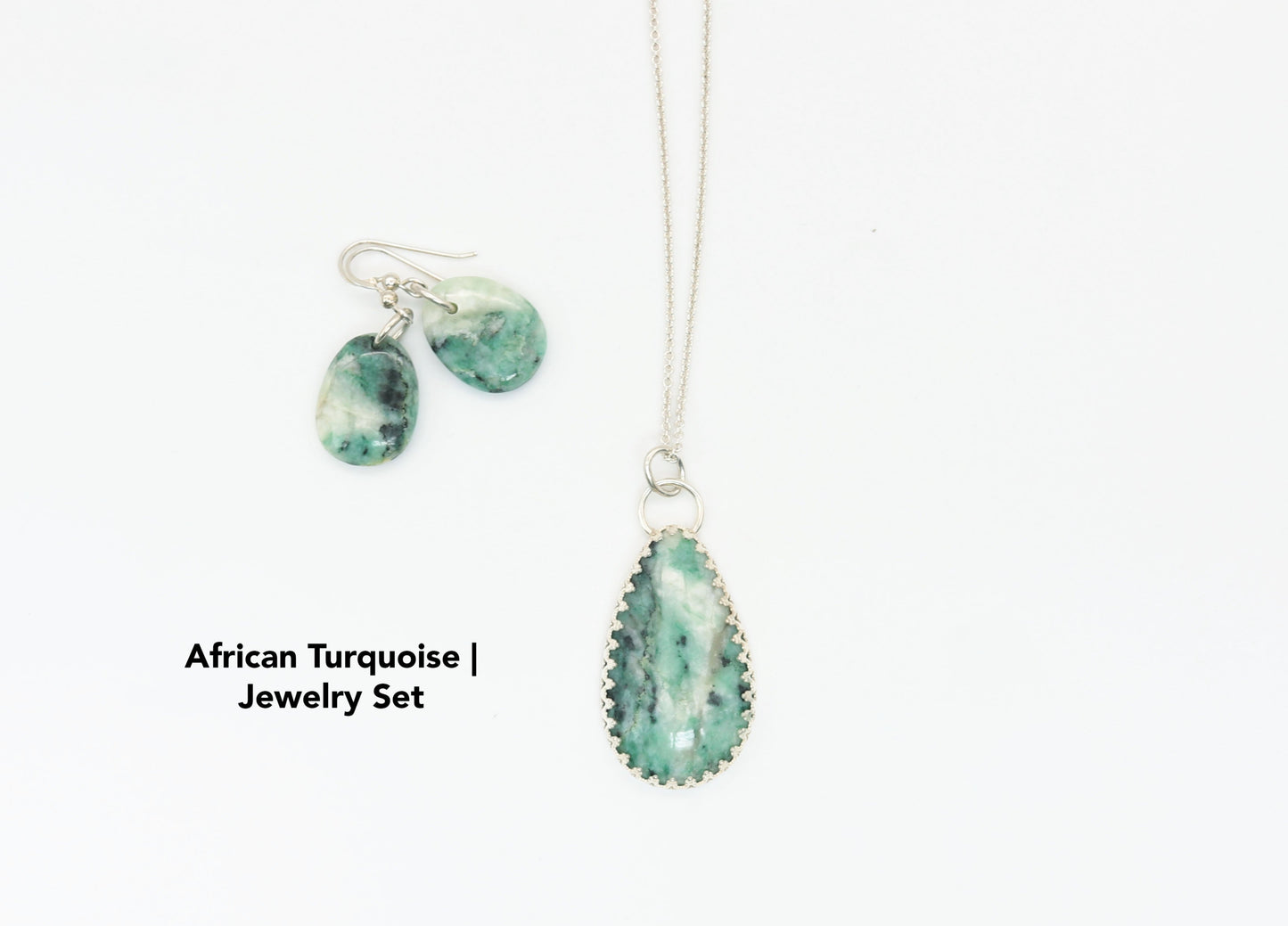 African Turquoise Jasper pendant is set in solid Argentium® 935 silver with a custom bezel, beautifully accented by a gallery-style border of inverted hearts. The jewelry is set on white background.