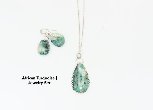 African Turquoise Jasper pendant is set in solid Argentium® 935 silver with a custom bezel, beautifully accented by a gallery-style border of inverted hearts.  The jewelry is set on white  background.