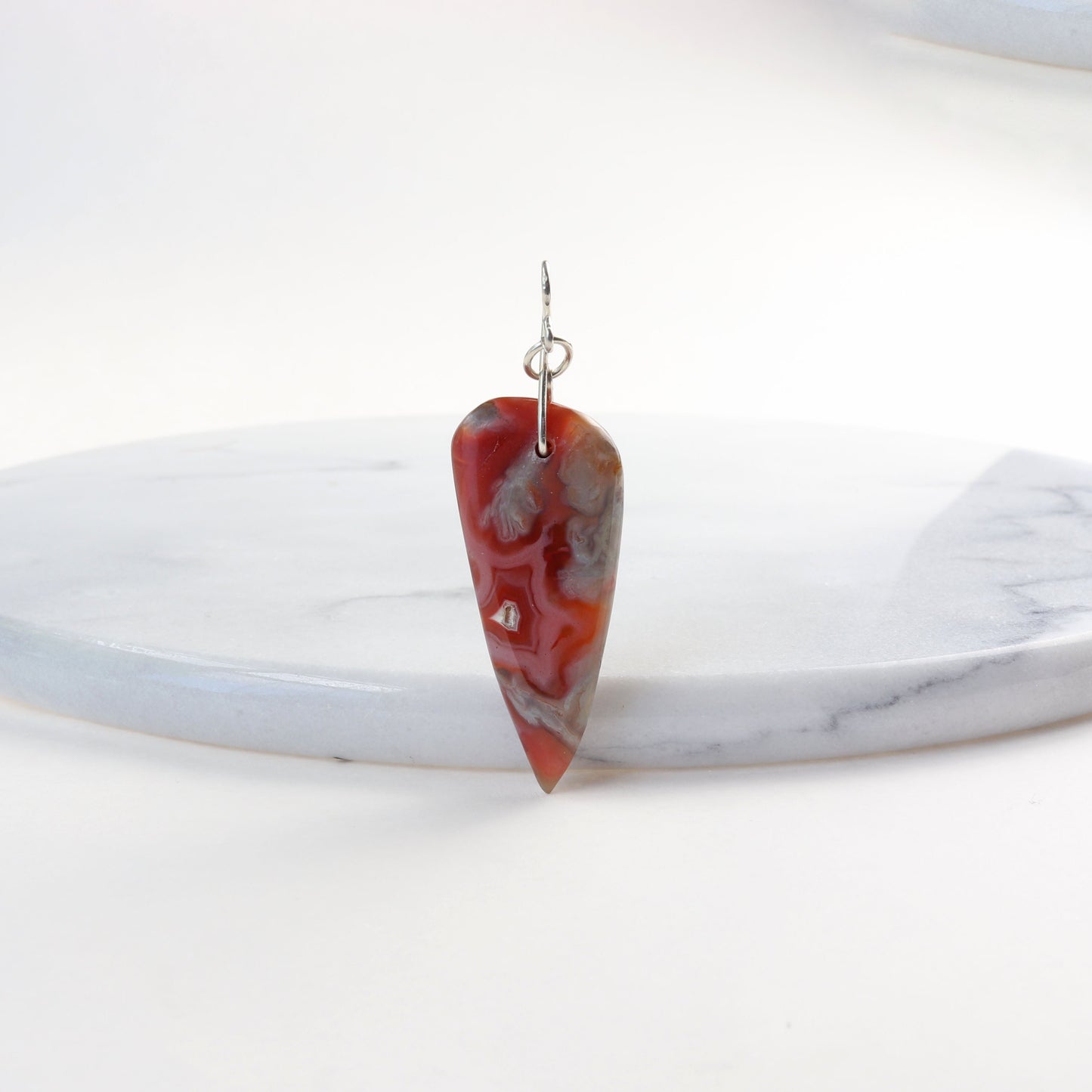 A Crazy Lace Agate arrow shaped gemstone pendant.
Handcut and freeform polished on both sides to reveal the unique swirling patterns and vibrant mauve deep reds and gray hues. Wear with complementary chain included or with you own favorite necklace.