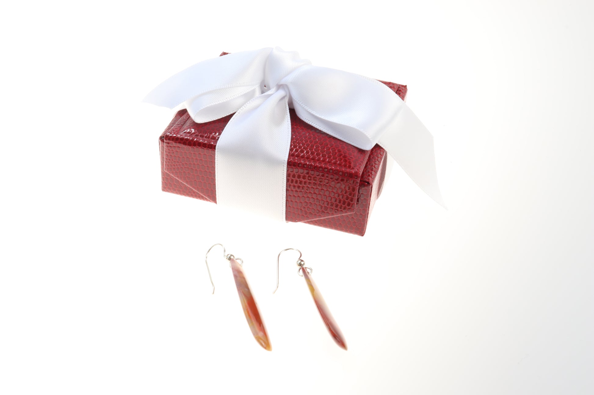 Earrings are shown against white background with red gift box with white satin ribbon.