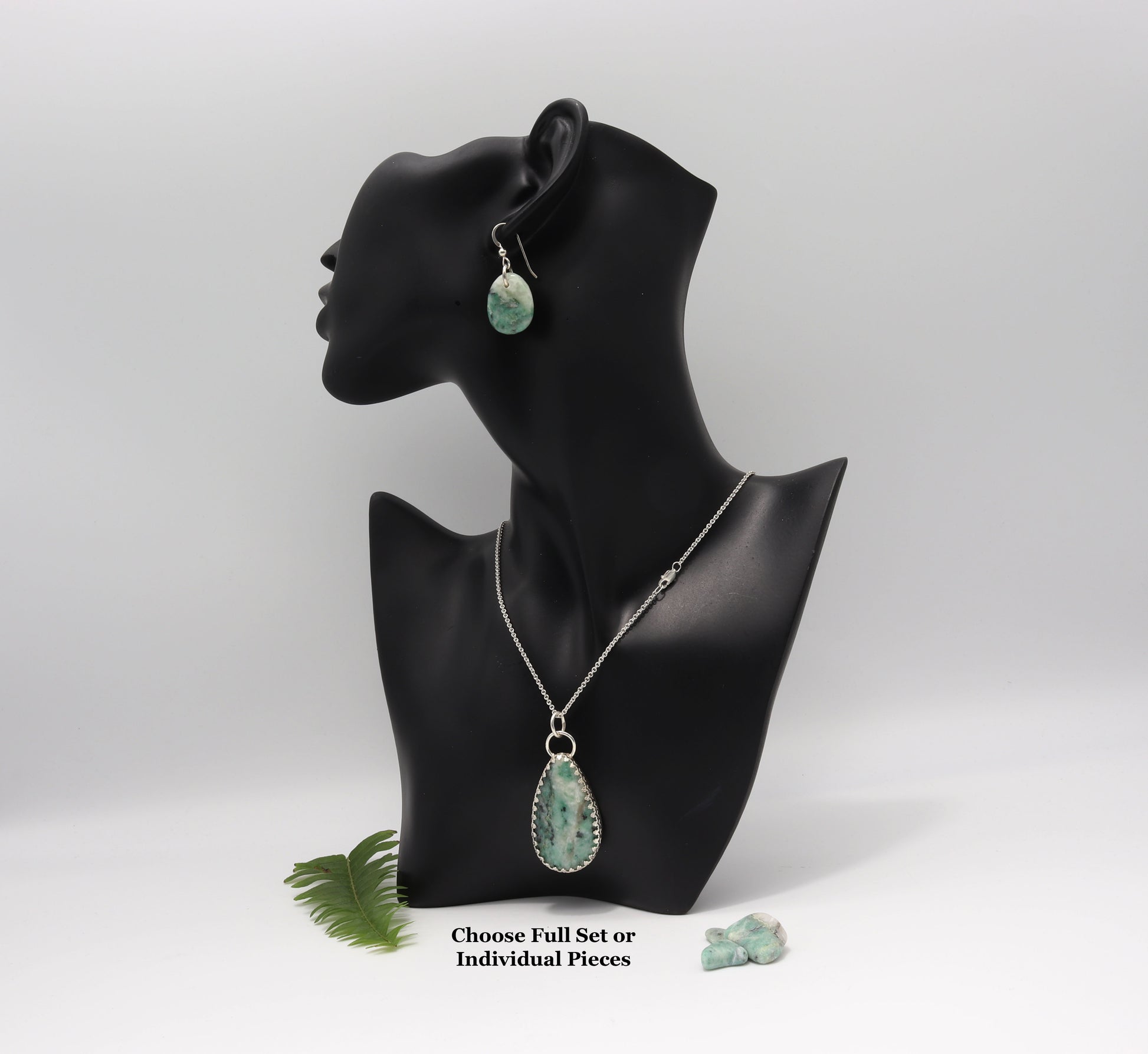 Handcrafted African Turquoise pendant and earrings set in recycled Argentium 935 silver display on black resin mannequin against a white background with a fresh fern and african turquoise chips in the lower right.