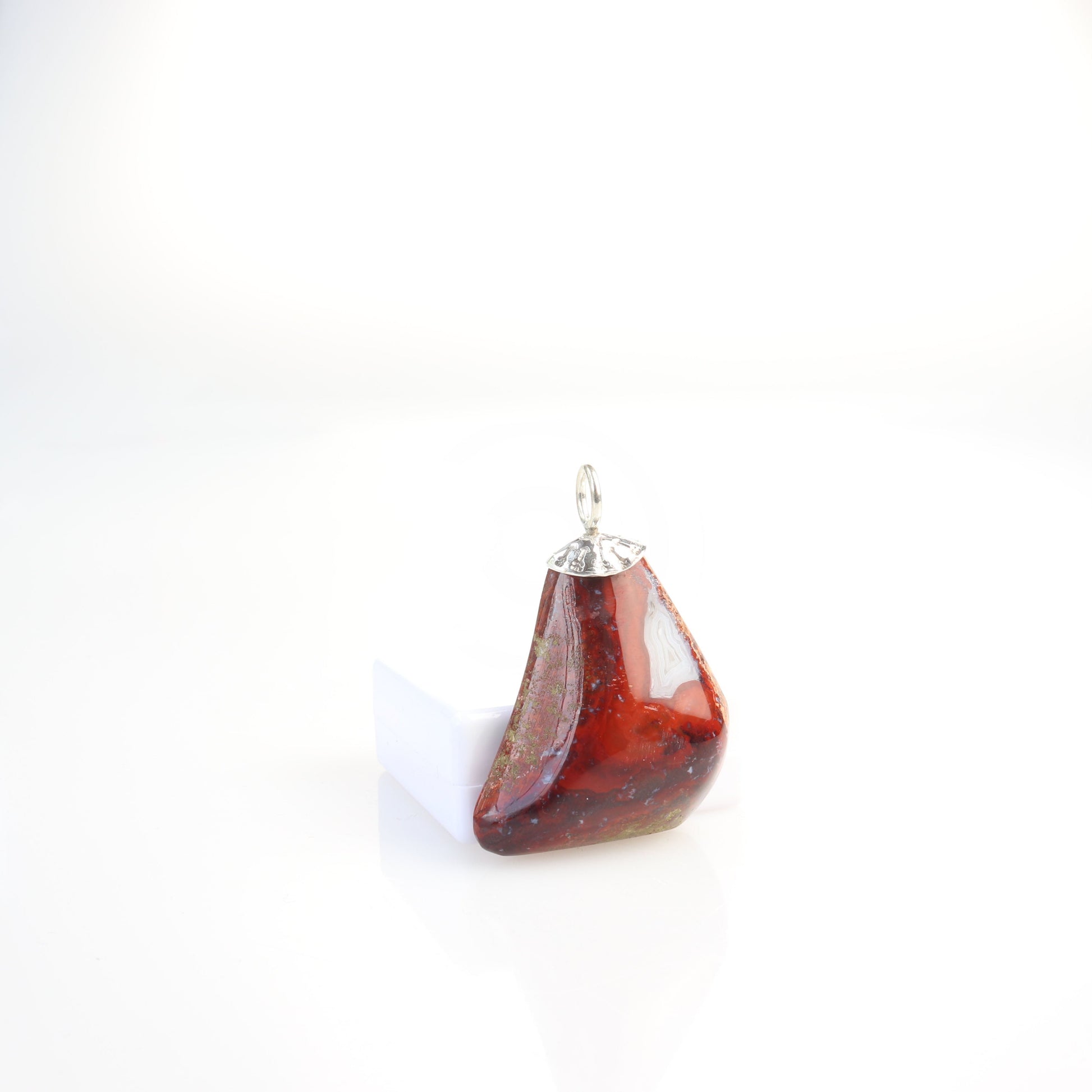 A 1.81 inch Red Jasper Agate Pendant, handcrafted in our small town Missouri studio. Handcut and freeform polished on both sides, showcasing the captivating patterns and rich red hues of this reversible piece. The custom crafted bail in sterling 935 Argentium Silver adds a touch of elegance.