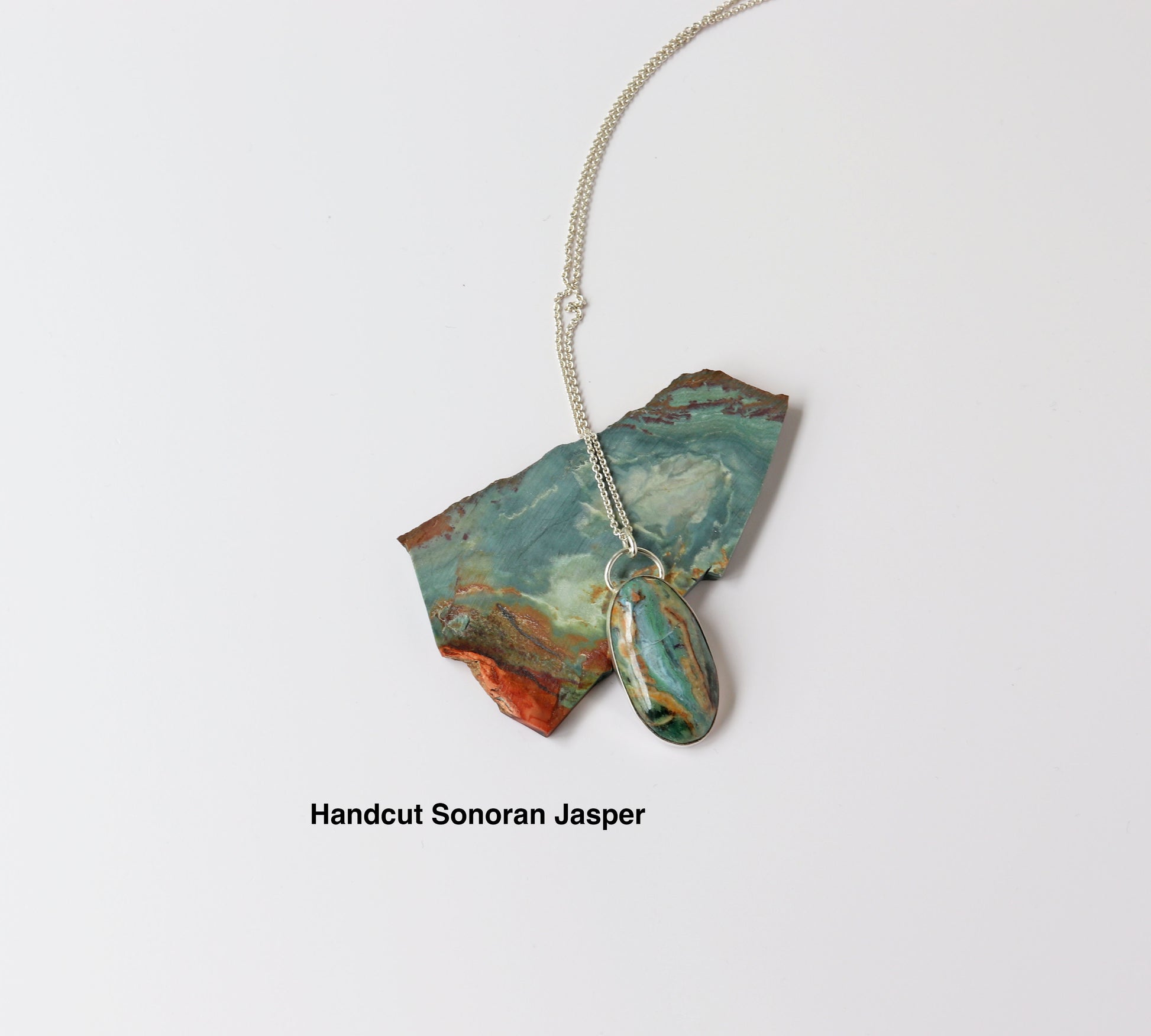Handcrafted Sonoran Jasper pendant displayed on matching stone slab, set in 935 Argentium® Silver.