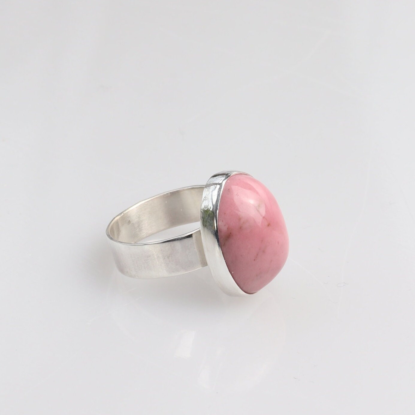 Side view of a Pink Rose natural Rhodonite gemstone set in fine silver bezel on a sterling 935 Argentium silver band.