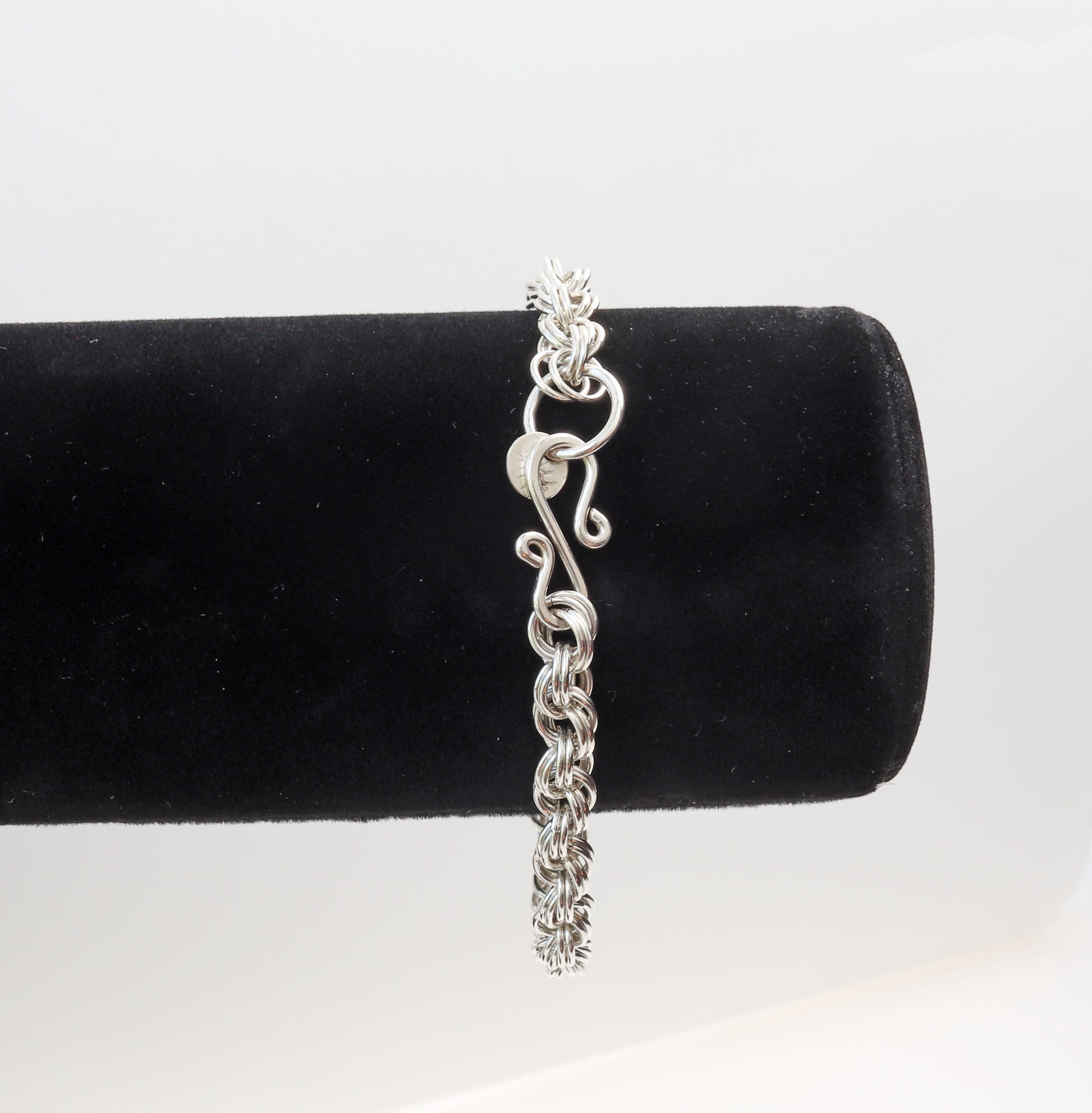 A close-up of the handcrafted vintage style S-Hook clasp. An exquisite 6mm Spiral Bracelet, meticulously crafted right here in our studio. This bracelet showcased on a black velvet bracelet form features the finest Argentium® 935 Silver featuring a stunning shine that is sure to captivate all who see it.