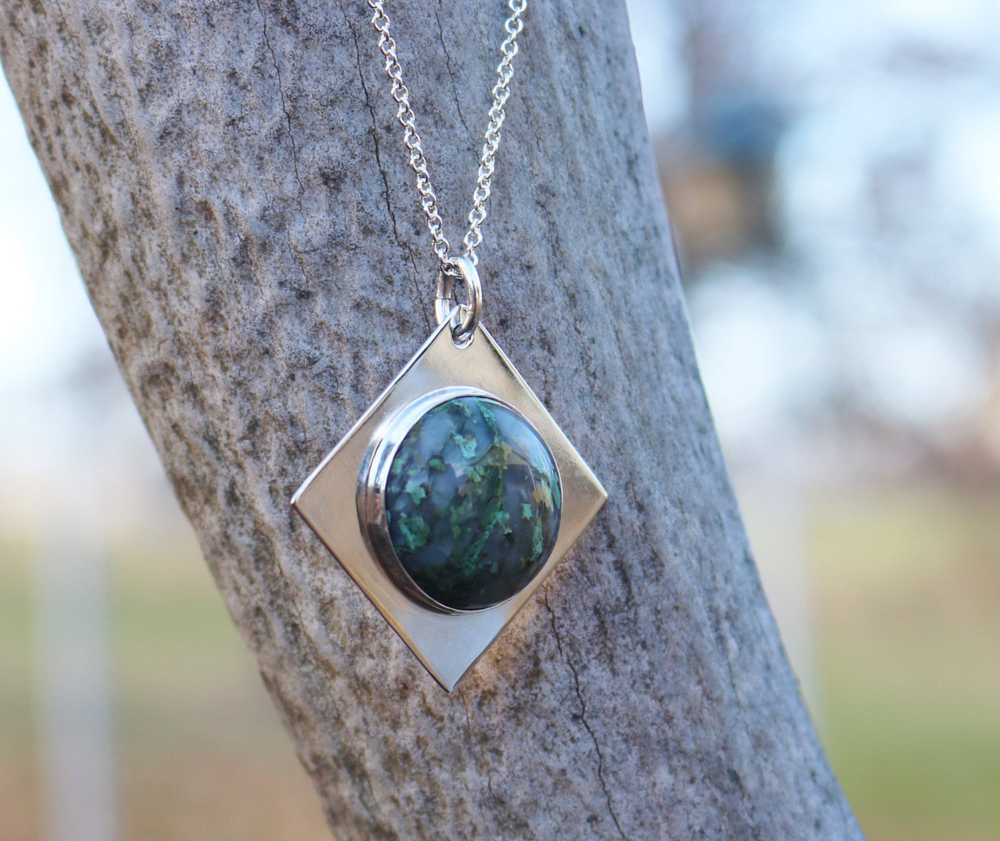 Variscite pendant shown hanging against an elk branch.
