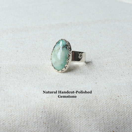 Handcut and polished natural African Turquoise gemstone ring in Argentium Silver shown on natural linen background with text overlay Natural Handcut Polished Gemstone.