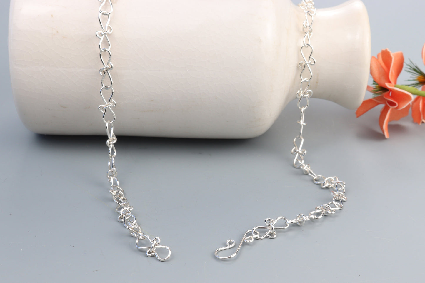 An Infinity bow shaped 18" Necklace.  Handcrafted in our Missouri studio, using solid 20 Gauge sterling 935 Argentium silver to create a piece that displays elegance and quality. The intricately woven bows symbolize eternal love and infinity, making this necklace a meaningful and heartfelt gift. Putting it on and taking it off is a breeze, thanks to the worry-free Easy S hook. The adjustable chain with 1/2 links allows you to customize the fit.