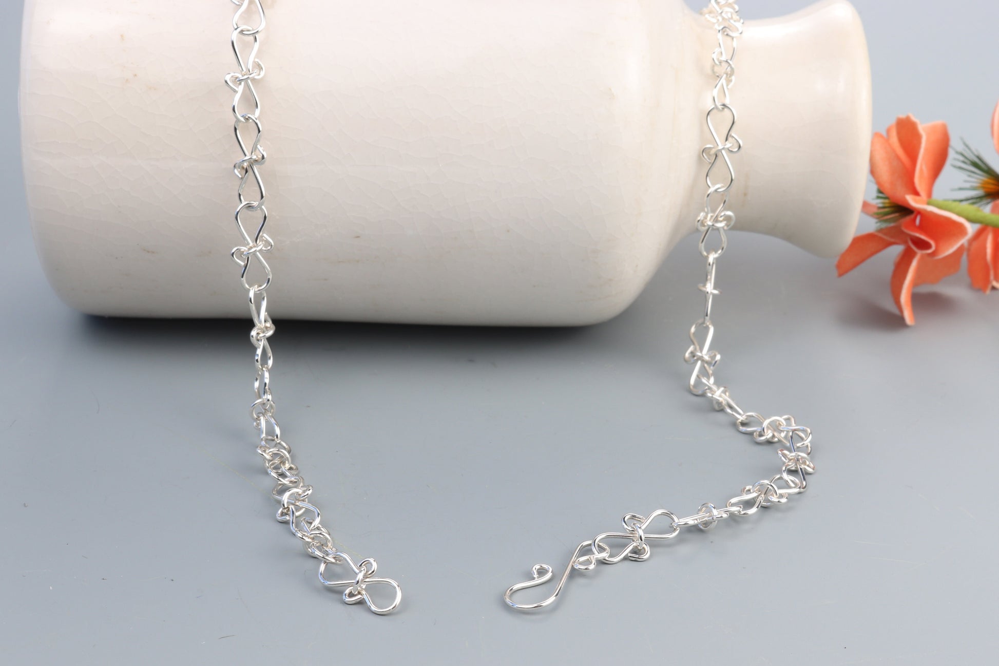An Infinity bow shaped 18" Necklace.  Handcrafted in our Missouri studio, using solid 20 Gauge sterling 935 Argentium silver to create a piece that displays elegance and quality. The intricately woven bows symbolize eternal love and infinity, making this necklace a meaningful and heartfelt gift. Putting it on and taking it off is a breeze, thanks to the worry-free Easy S hook. The adjustable chain with 1/2 links allows you to customize the fit.