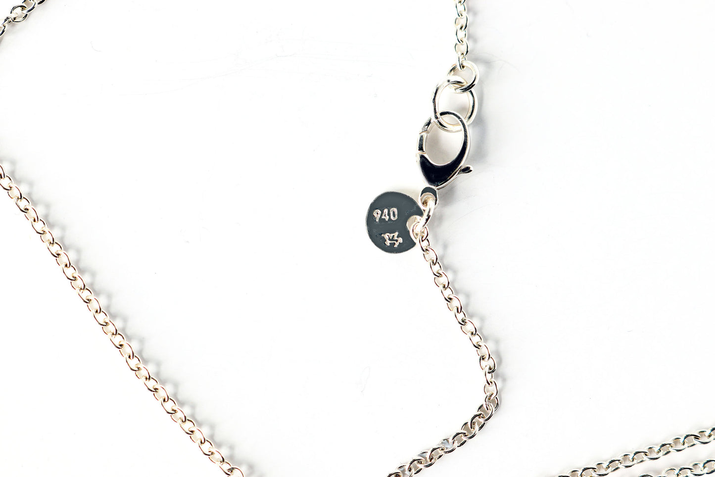 Argentium Silver necklace with the Argentium Winged Unicorn® hallmark tag with 940 — attached to a oval chain necklace with sterling silver .925 teardrop clasp on a white background