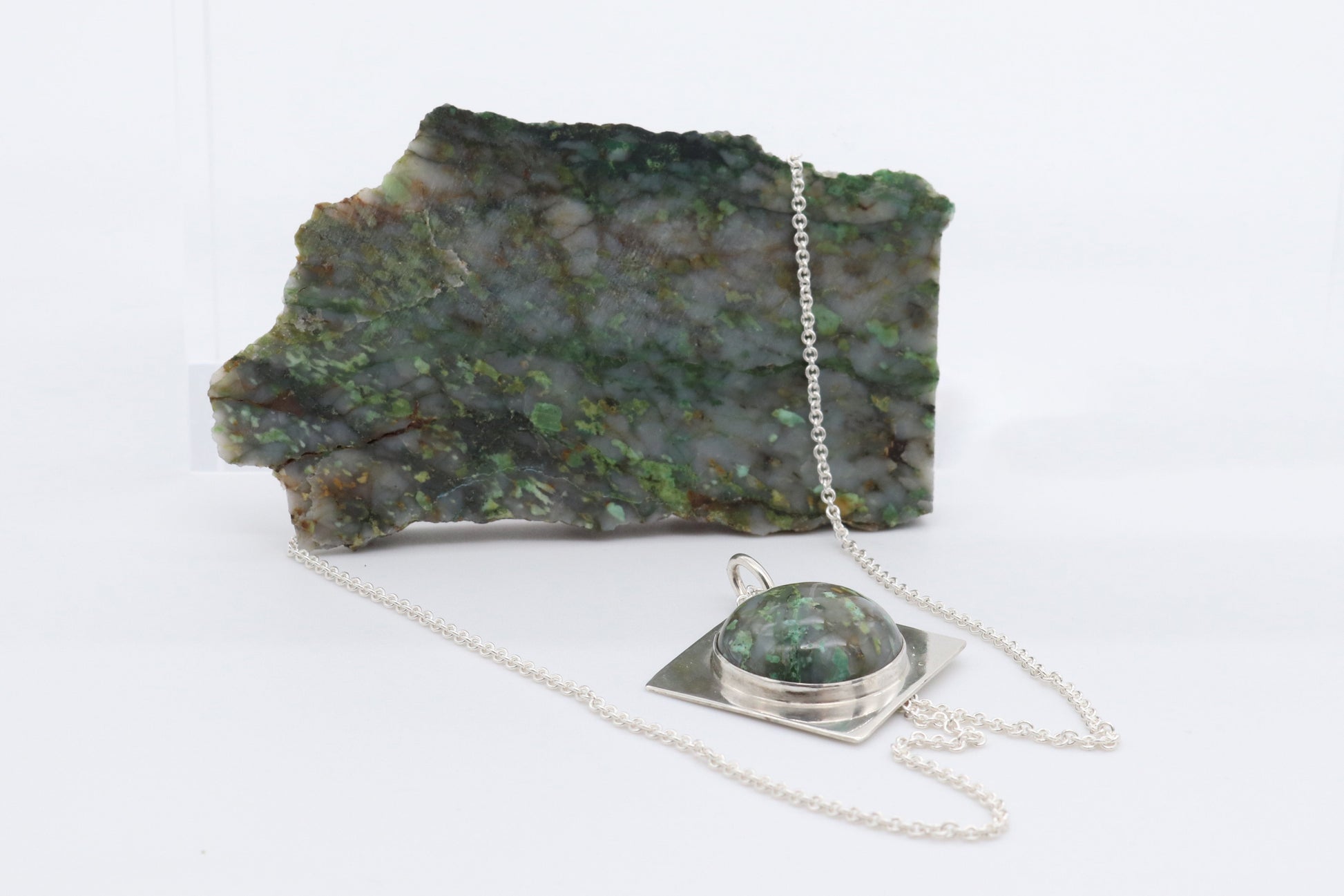 Raw Variscite rock used to craft pendant shown on white background.