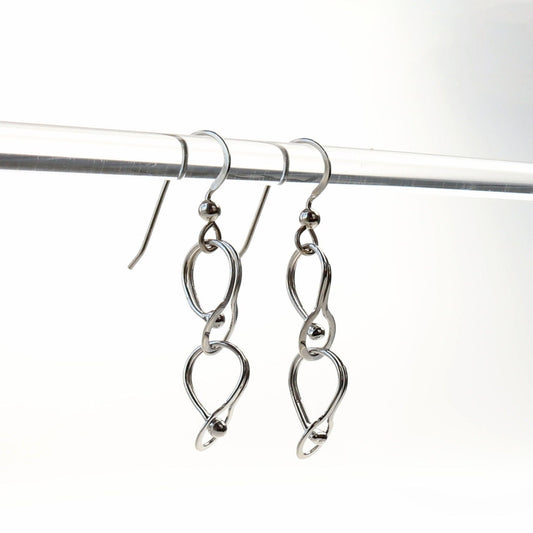 Double loop dangle earrings handcrafted in Argentium® 940 silver, featuring two twisted open loops linked vertically. Displayed hanging from a clear rod.