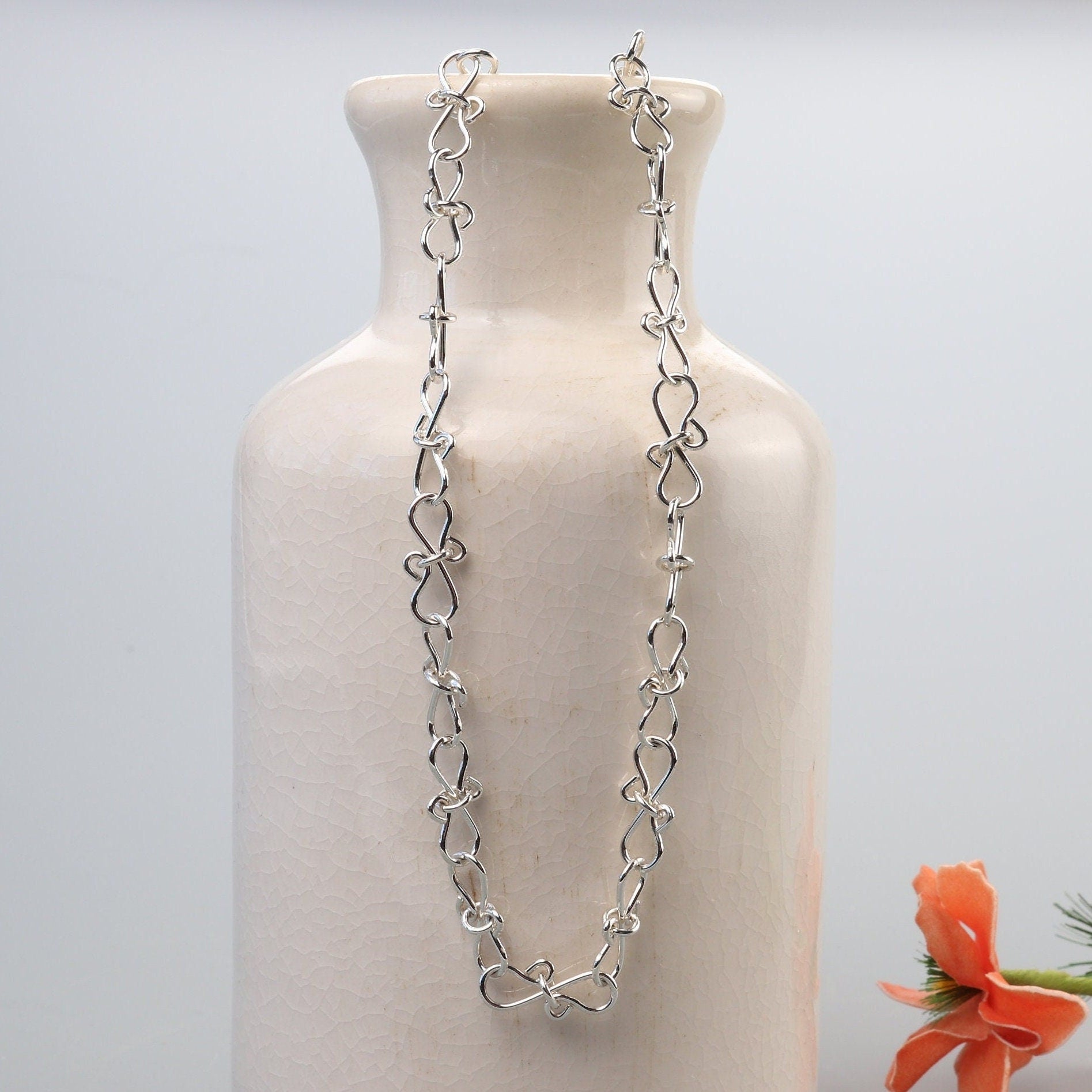 An Infinity bow shaped 18" Necklace.  Handcrafted in our Missouri studio, using solid 20 Gauge sterling 935 Argentium silver to create a piece that displays elegance and quality. The intricately woven bows symbolize eternal love and infinity, making this necklace a meaningful and heartfelt gift. Putting it on and taking it off is a breeze, thanks to the worry-free Easy S hook. The adjustable chain with 1/2 links allows you to customize the fit.