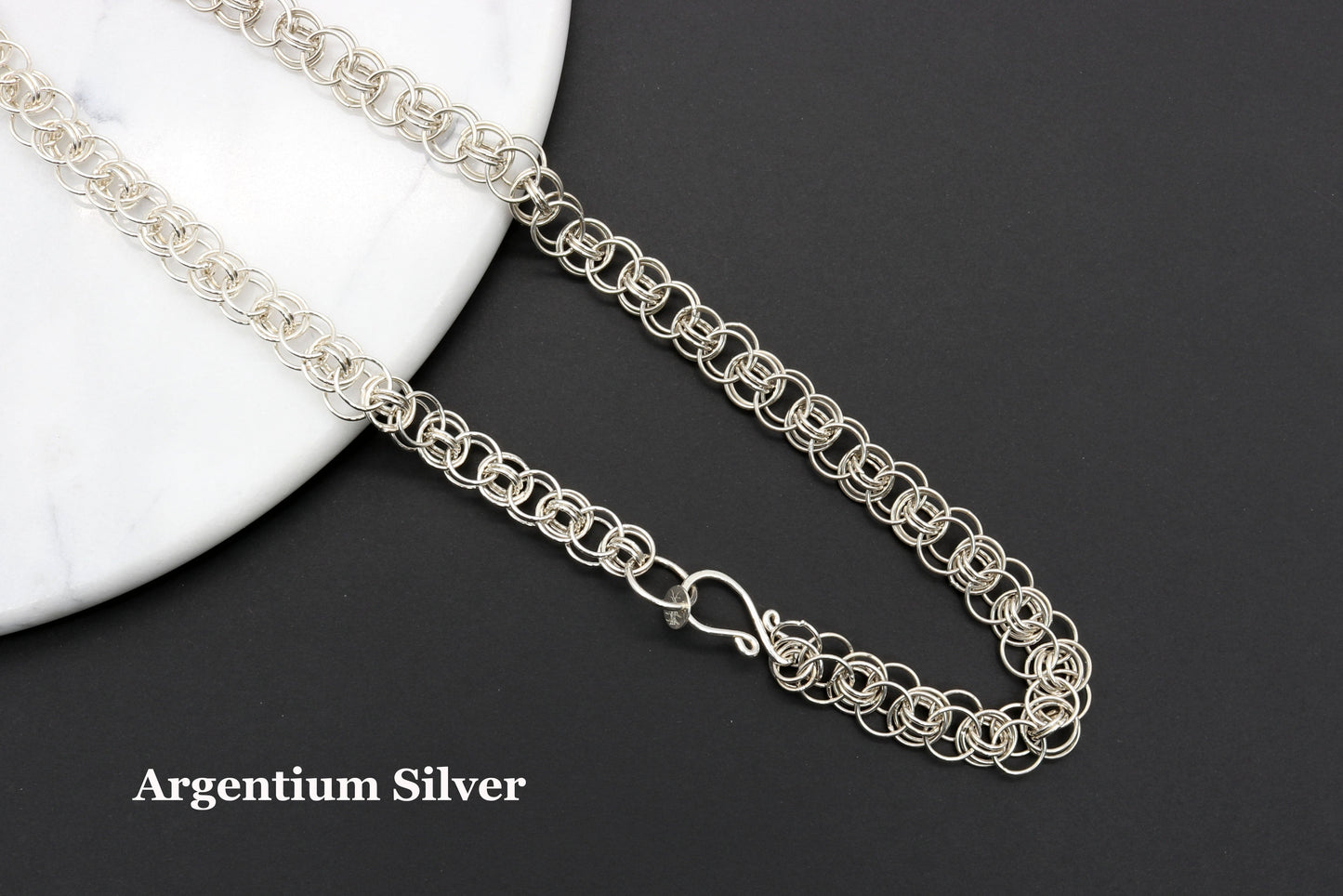 Handmade helm weave chainmaille  in premium Argentium silver draped over marble resting on a black background to highlight the brilliant shine of Argentium Silver.