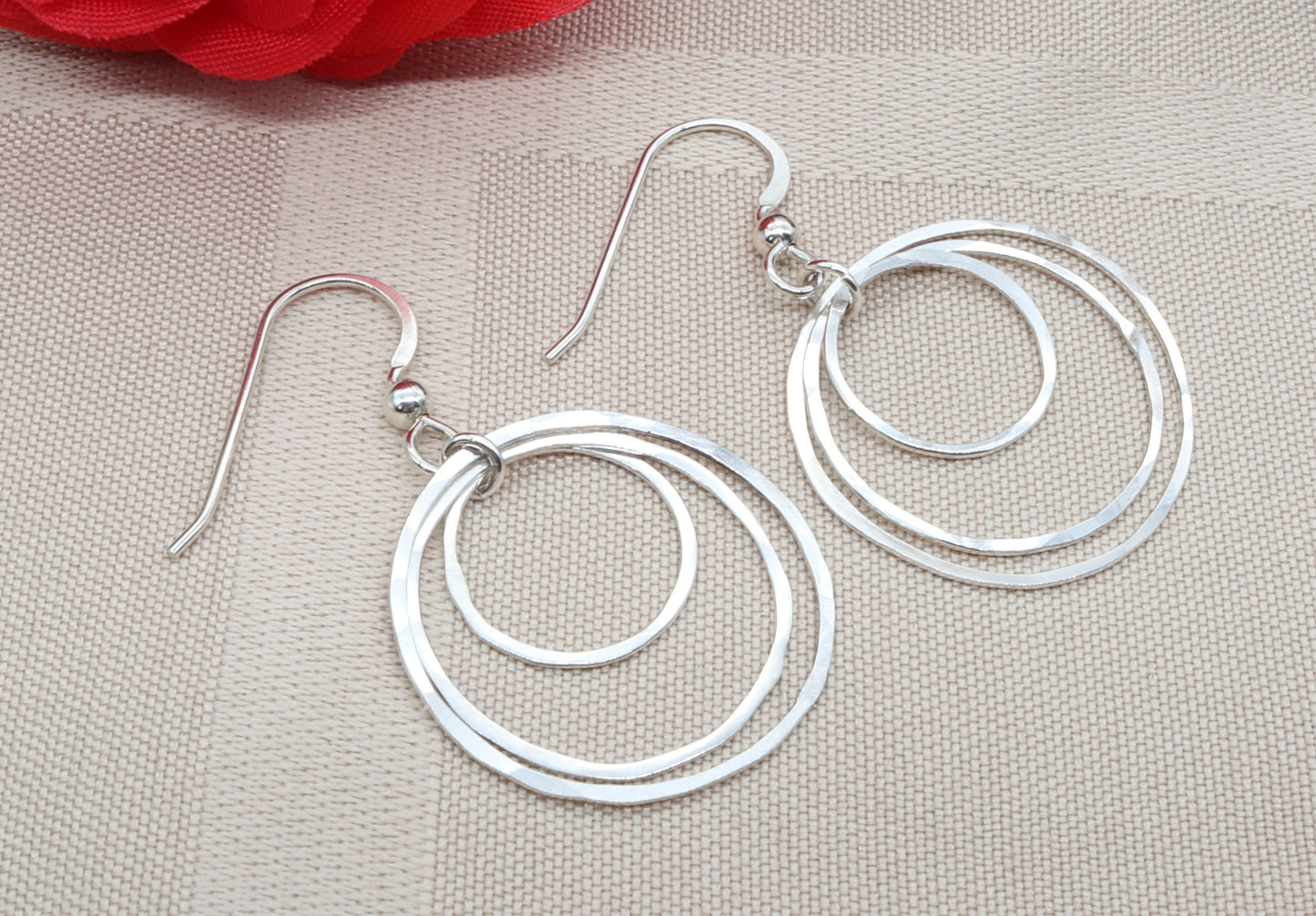 Handcrafted hammered hoop earrings. Made Argentium® 935 silver, these tarnish-resistant earrings are designed to last while maintaining their brilliant finish. Shown on beige linen background.