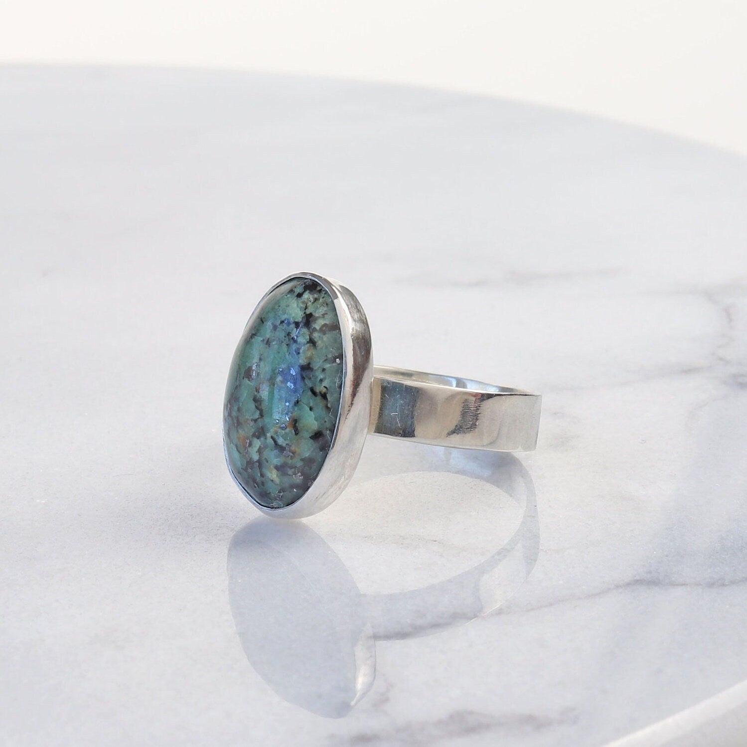 A one-of-a-kind Fraser River Turquoise ring features a handcut and polished gemstone with stunning blue-green hues and bold black mottled matrix, echoing the rugged landscape of the Fraser River region in British Columbia