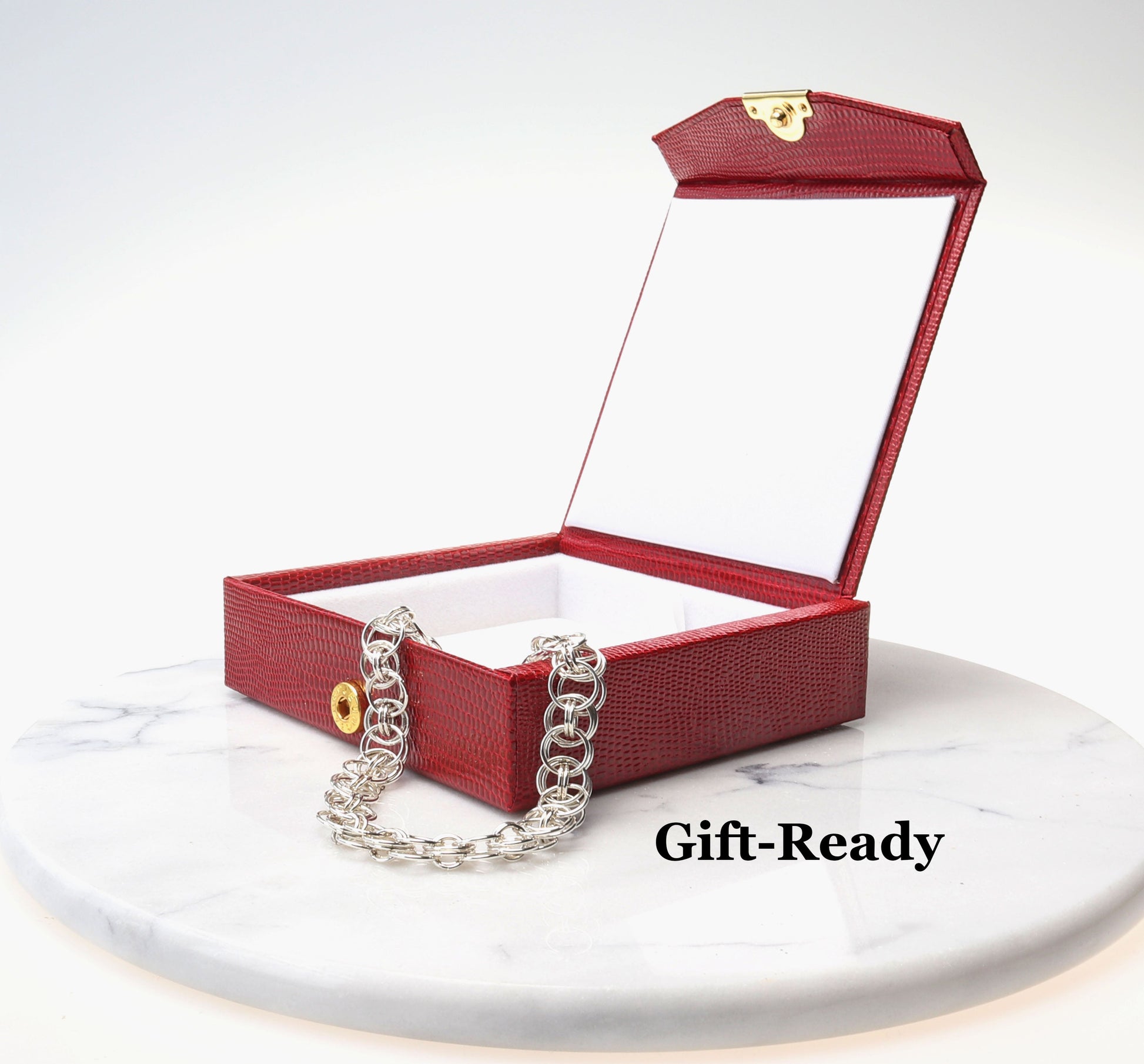 Bracelet comes packaged in a red faux leather stylish gift box shown open with bracelet draped over opening against a white background placed on top of white marble.  Ready to gift.