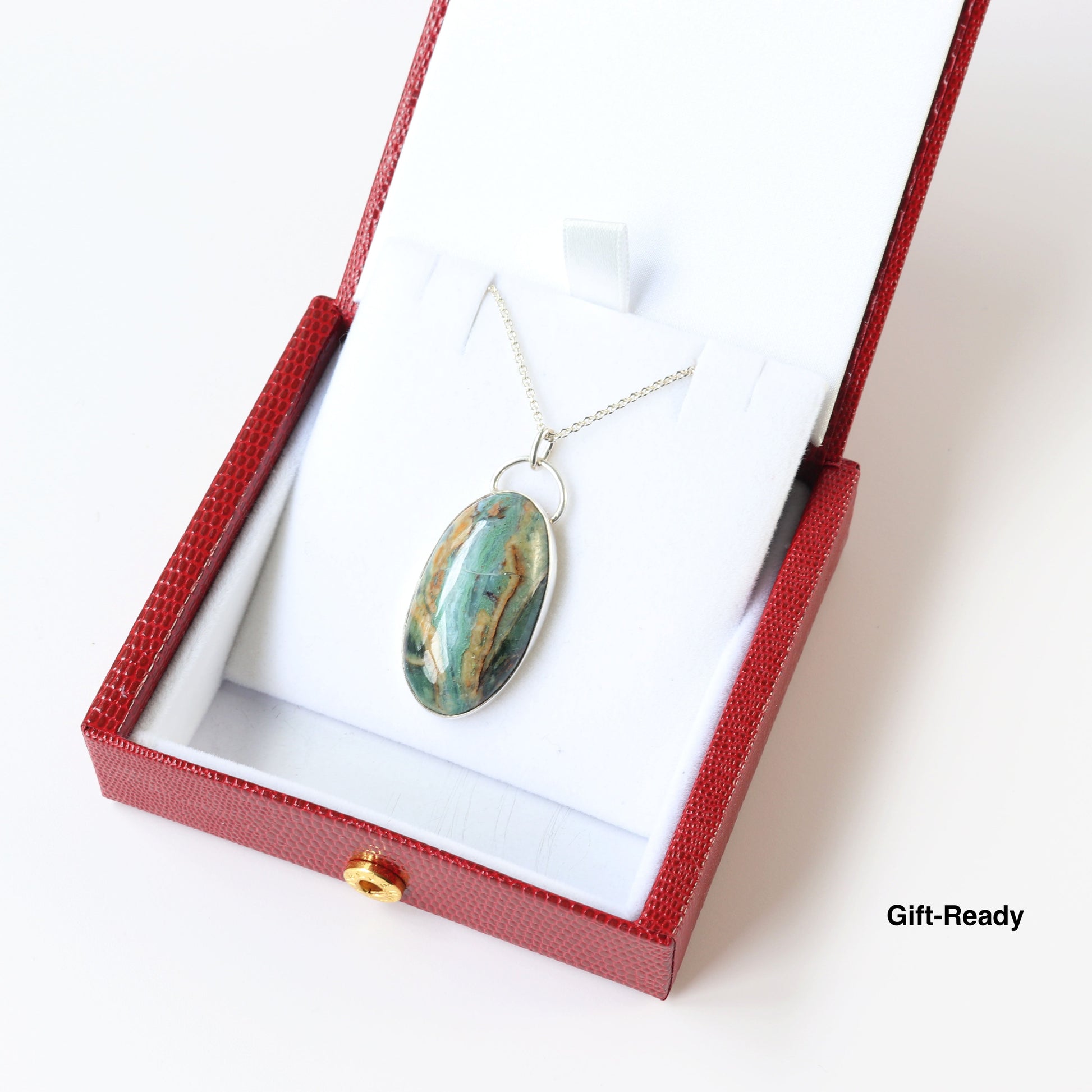 Gift-boxed handcrafted Sonoran Jasper pendant features teal and earthy brown tones pendant set in 935 Argentium® Silver with chain shown.  Pendant comes in stylish red faux leather gift box with text overlay Gift-Ready.