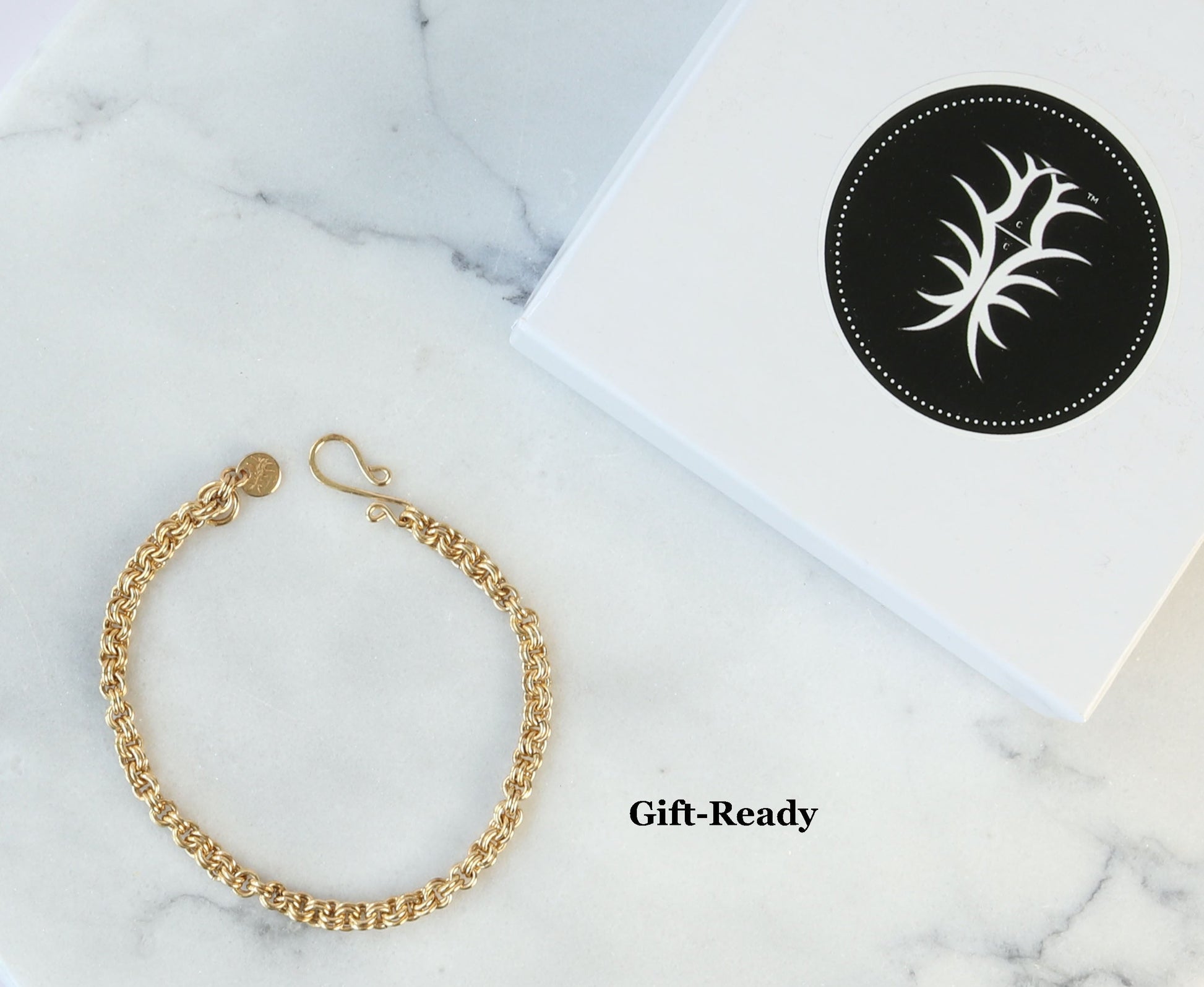 Handmade chainmail bracelet in Jewelers Brass shown next to Signature gift Box against white marble background.  Ready Gift or for personal   storage.