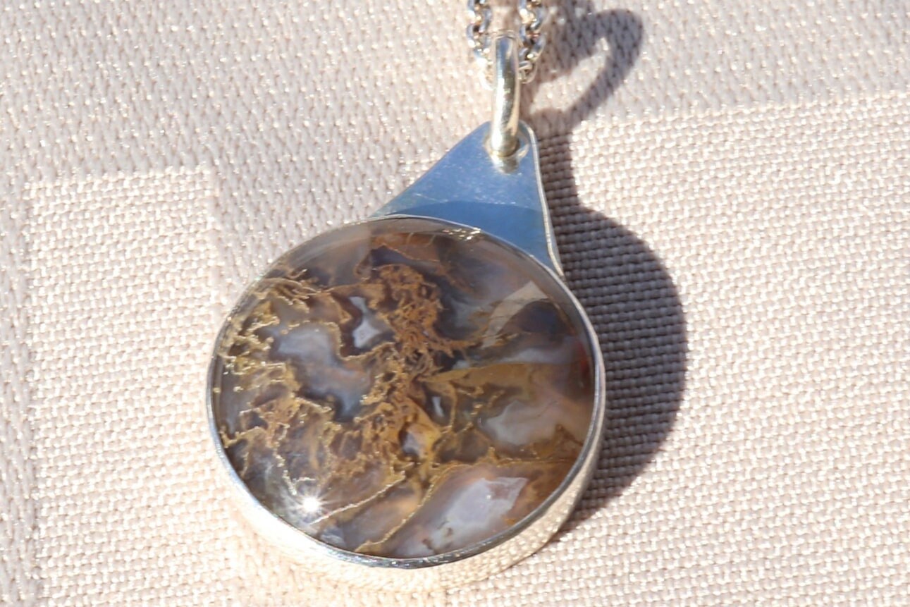 A 1 inch Rutilated Quartz gemstone with brown and golden-colored needle-like inclusions artistry. The gemstone is encased in a meticulously crafted Argentium® 935 Silver; an ideal complement to any personal collection.