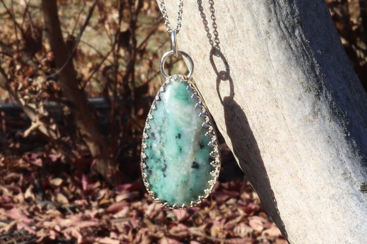 A natural 2.12 inch African Turquoise gemstone, handcut and polished in our Missouri studio to reveal its earthy patterns and hues of teal, green and creamy white. Reminiscent of real turquoise, this African Turquoise gemstone boasts its own unique patterns and variations, making every piece truly one-of-a-kind. Set in a custom 935 Argentium setting paired with a complementary 18 inch chain.