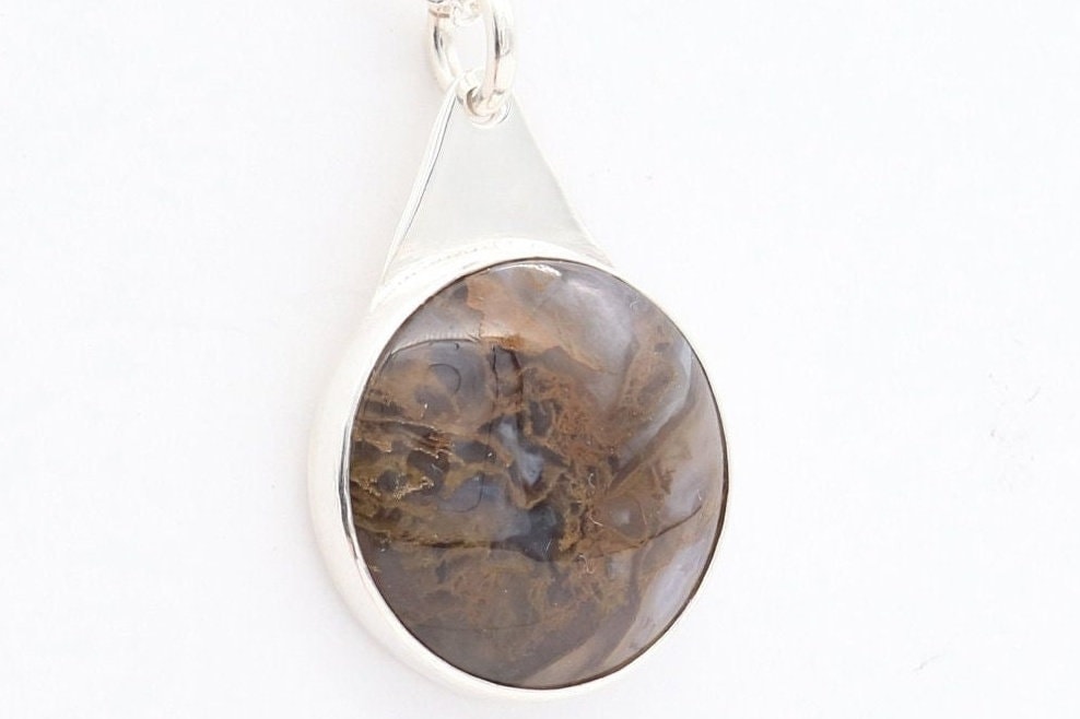 A 1 inch Rutilated Quartz gemstone with brown and golden-colored needle-like inclusions artistry. The gemstone is encased in a meticulously crafted Argentium® 935 Silver; an ideal complement to any personal collection.