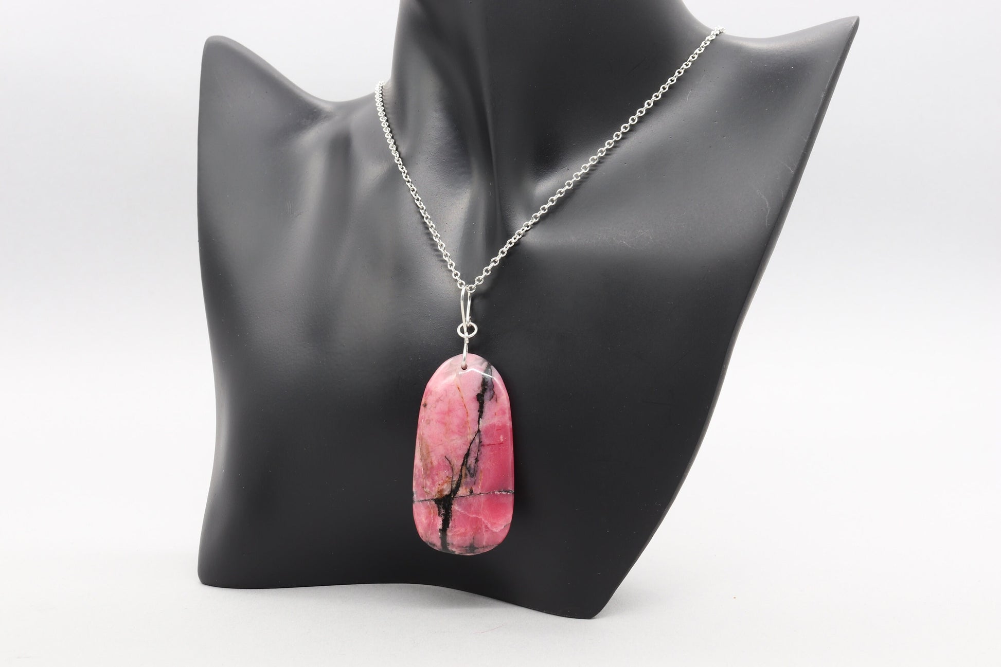 A polished Rhodonite pendant on both sides and features a handcrafted infinity bow-shaped bail made from hypoallergenic, tarnish-resistant Argentium® 935 silver.  Chain not included.
