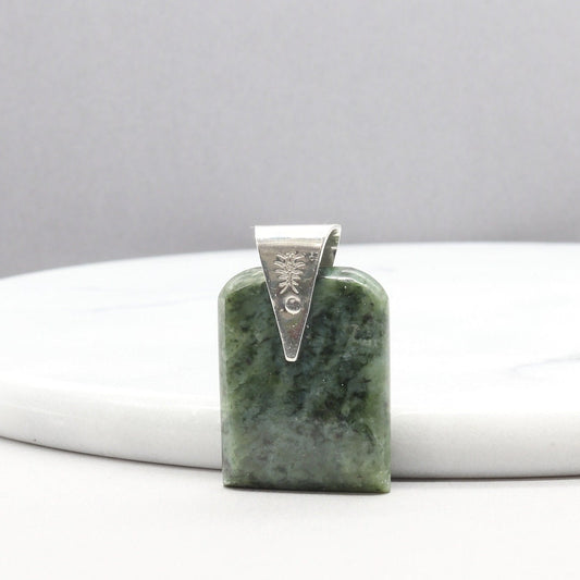 A Wyoming (Nephrite) Jade that I shaped and polished to bring out the light to dark sage translucent colors and patterns, into a distinctive tombstone tag shape. The custom-crafted bail with the Elkhorn Silver™ Crest makers mark, is sculpted from tarnish resistant and hypoallergenic sterling Argentium® 935 Silver.