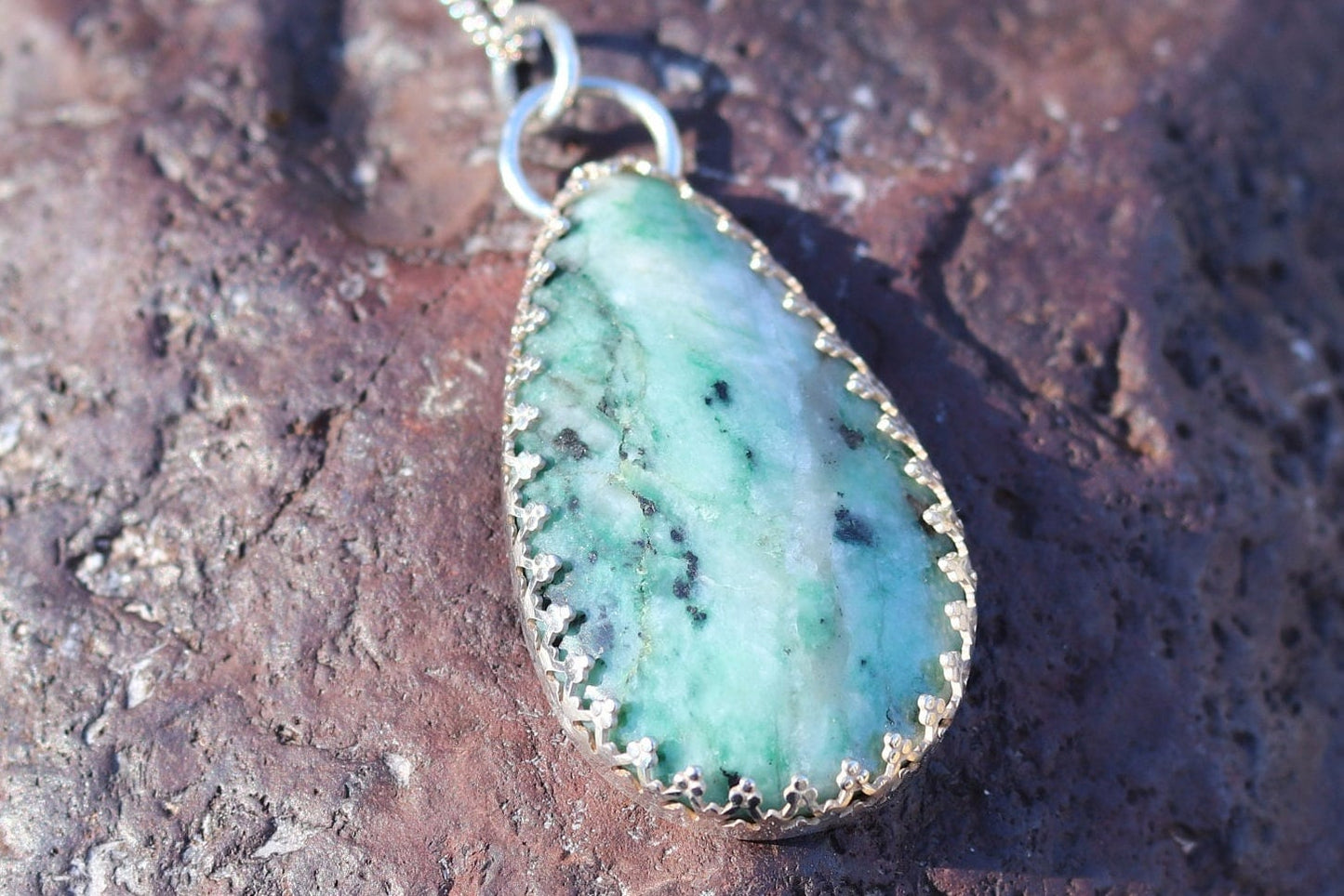 A natural 2.12 inch African Turquoise gemstone, handcut and polished in our Missouri studio to reveal its earthy patterns and hues of teal, green and creamy white. Reminiscent of real turquoise, this African Turquoise gemstone boasts its own unique patterns and variations, making every piece truly one-of-a-kind. Set in a custom 935 Argentium setting paired with a complementary 18 inch chain.