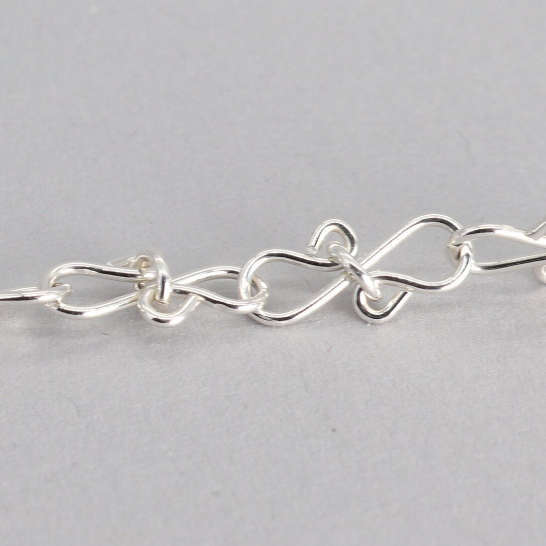 Infinity bow shaped chain bracelet handcrafted from solid sterling 935 Argentium Silver, ensuring its resistance to tarnish while being hypoallergenic for sensitive skin. The bracelet measures 7.5 in length, with an adjustable design that allows you to find the perfect fit by increments of half inch. A custom S hook clasp that enables easy wearing and removal.