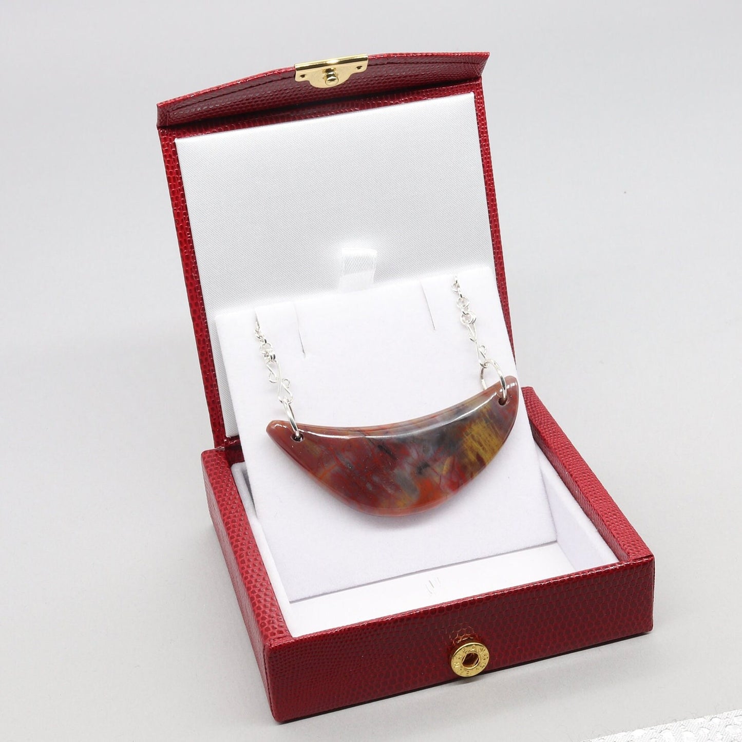 A piece of Arizona's history in this stunning sterling Petrified Rainbow Wood crescent moon pendant. Handcrafted with sterling Argentium® Silver 935 bow shaped dual wire bails and single cable chains. Handcut and polished into a moon shaped crescent to reveal the remarkable translucent colors and patterns of nature's artistry on both sides of the pendant. Ready to gift in a red faux leather stylish gift box.