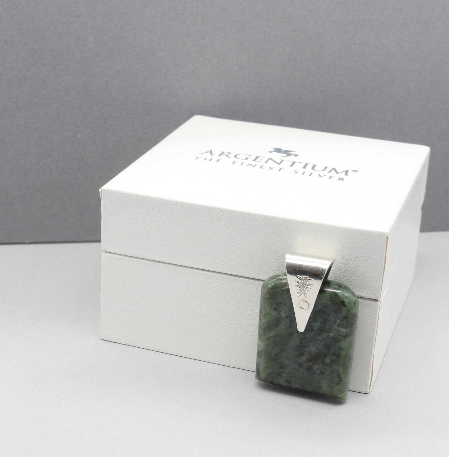 A Wyoming (Nephrite) Jade that I shaped and polished to bring out the light to dark sage translucent colors and patterns, into a distinctive tombstone tag shape. The custom-crafted bail with the Elkhorn Silver™ Crest makers mark, is sculpted from tarnish resistant and hypoallergenic sterling Argentium® 935 Silver.  Ready to gift in a stylish gift box.