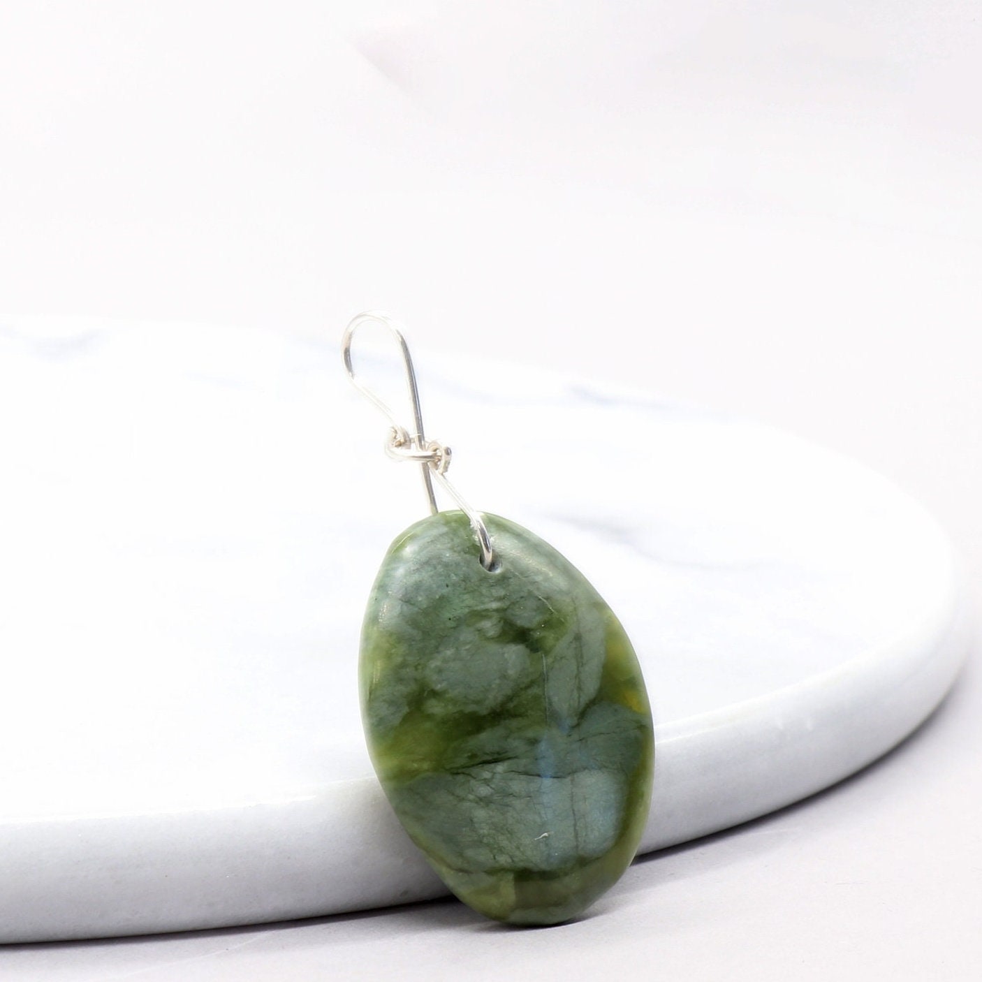 A California Jade gemstone pendant. Handcut and polished to showcase its unique translucent qualities, green hues and striking patterns on both sides. The pendant is designed with an original infinity bow shaped wire bail made from sterling Argentium® 935 Silver that is tarnish resistance and has a remarkable shine. The complete the look a complementary 935 Argentium silver chain is included.