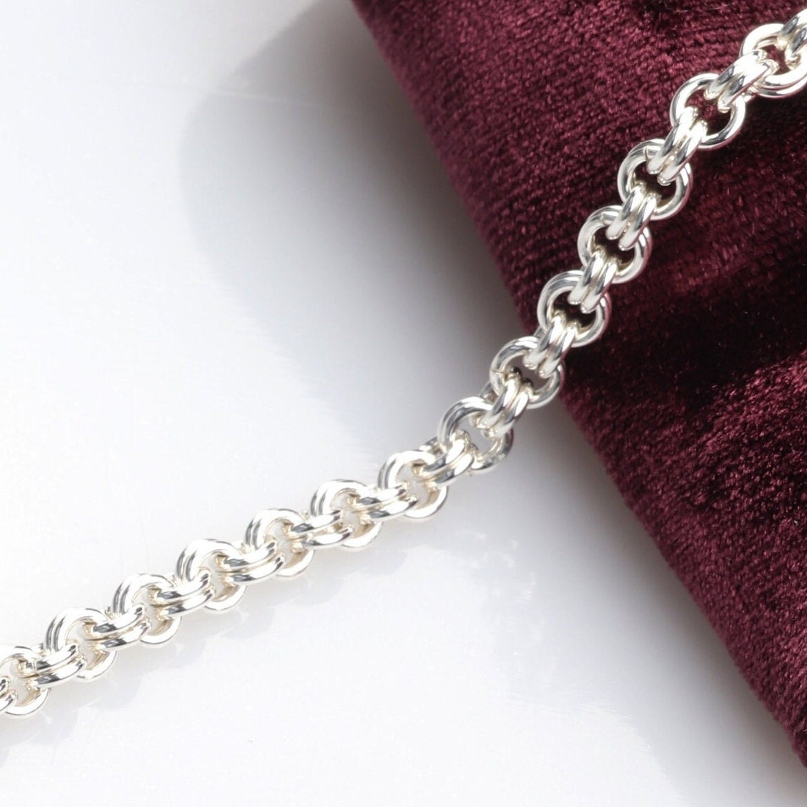 A handcrafted double cable chain bracelet in solid sterling 935 Argentium solid silver. This eye-catching double cable weave bracelet features a magnetic clasp that holds securely, yet opens and closes easily. sterling Argentium 935 is known for its tarnish resistant hypoallergenic qualities and contains more pure silver than the typical .925 Sterling silver. A section of bracelet is shown draped across burgundy velvet.