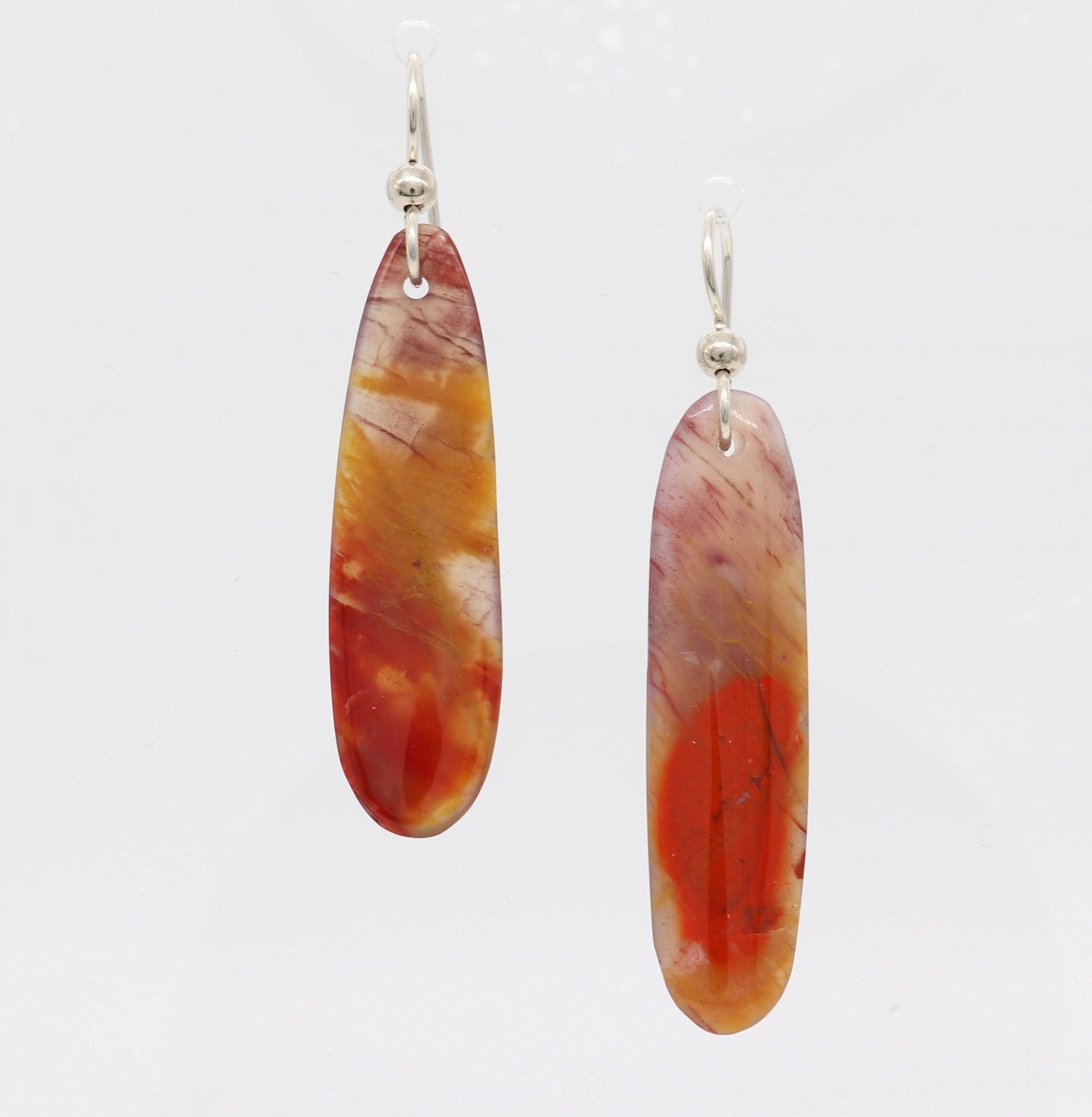 Expertly Handcut and polished Arizona Petrified Rainbow Wood reveals a stunning array of natural reds, oranges, golds, and mauves in these captivating translucent earrings. Accentuating the organic beauty of the wood, the earrings are paired with premium .935 Argentium® Silver ear wires, offering both elegance and a secure, comfortable fit.