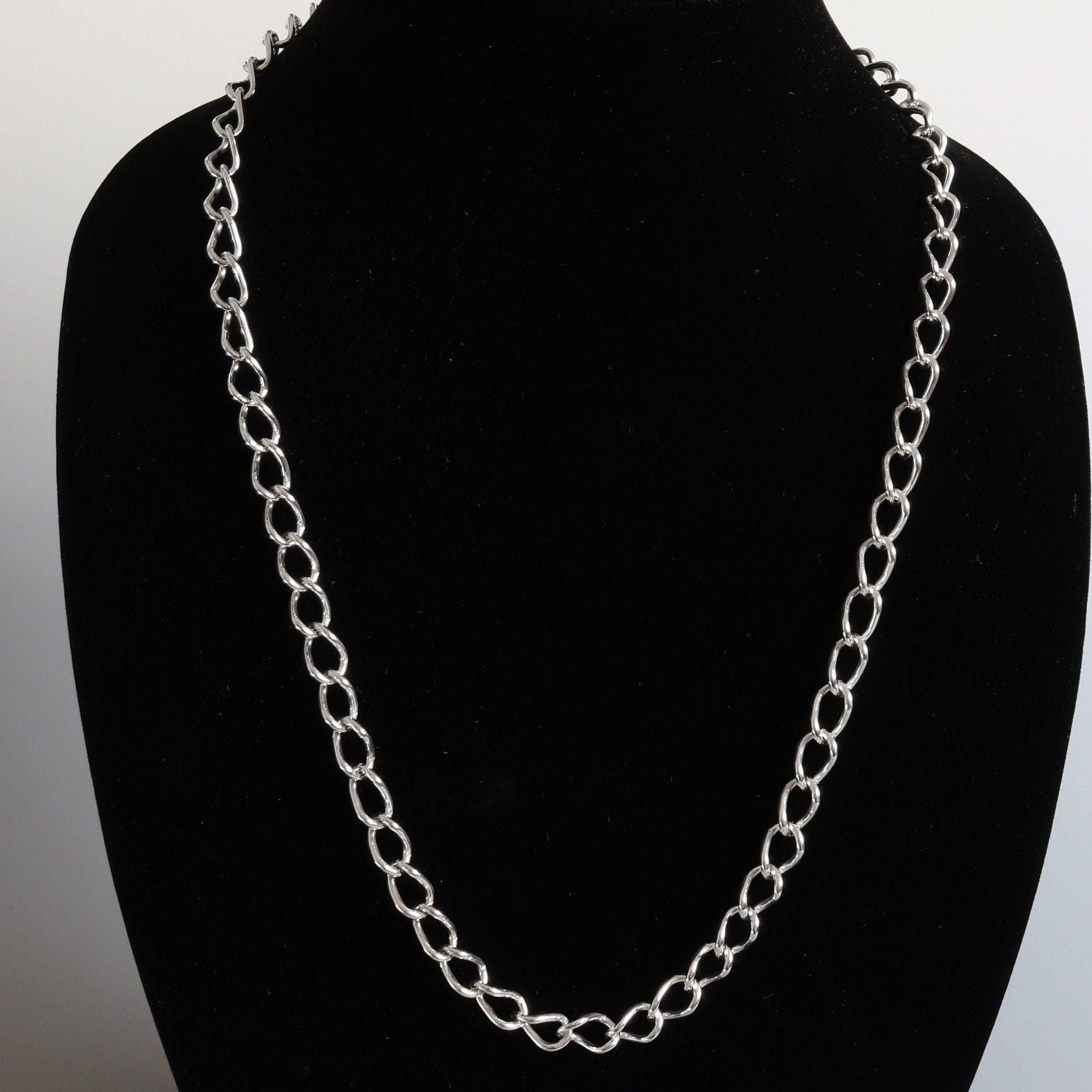 A sterling 940 Argentium handcrafted Oval Link Chain. With a length of 24 inches and a substantial 15mm width, this necklace is a bold statement piece, weighing a solid 45 grams. It's constructed from over 65 rings, each expertly woven together in our Missouri studio to form a classic design. The custom shepherd's hook clasp guarantees easy wearability, and your chain will arrive in a stylish gift box, ready for gifting or safekeeping.