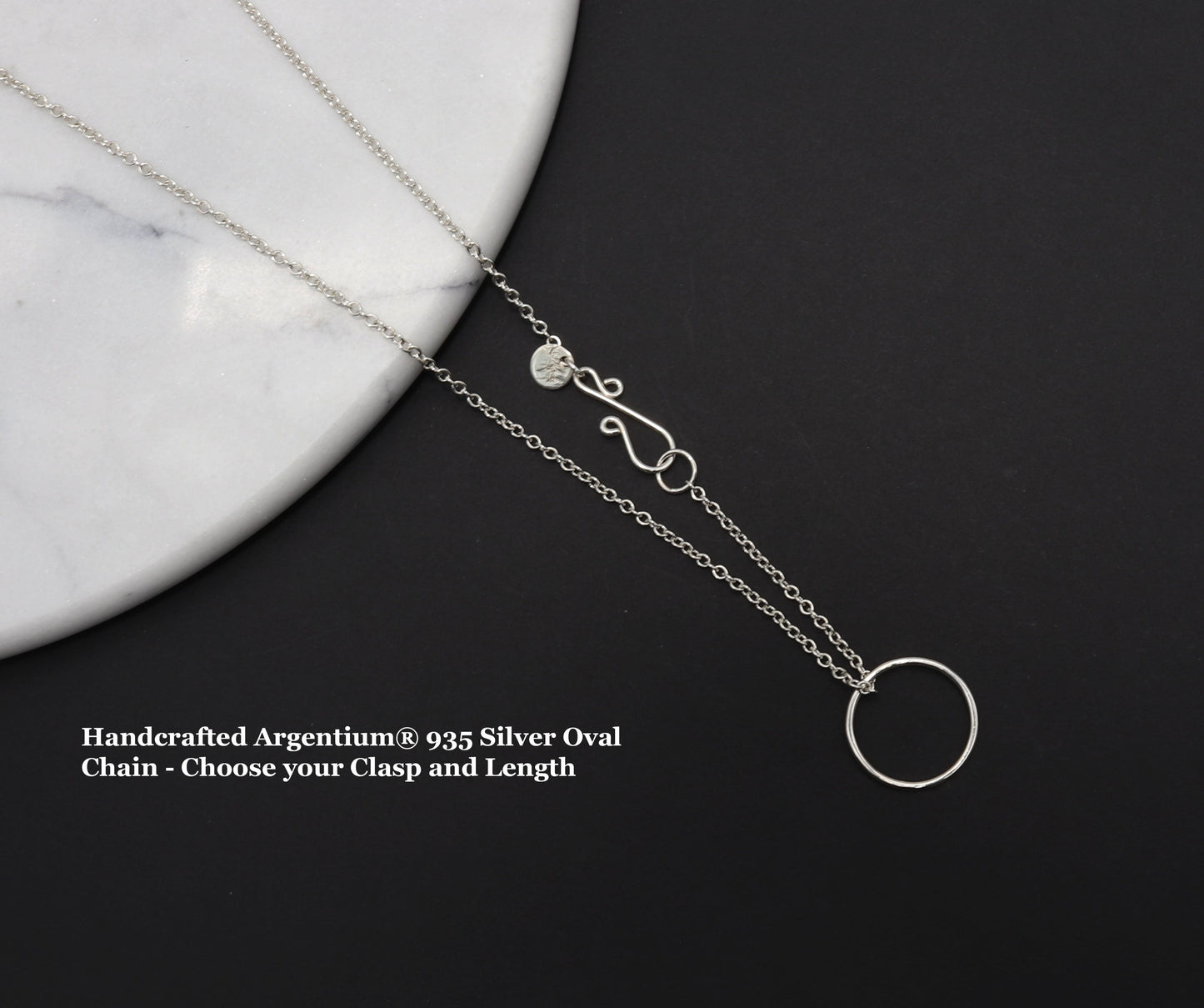 This handcrafted Open Circle Necklace shown on black background against white marble, is created using 100% recycled Argentium® 935 silver—brighter than traditional sterling, hypoallergenic, and tarnish-resistant by nature.