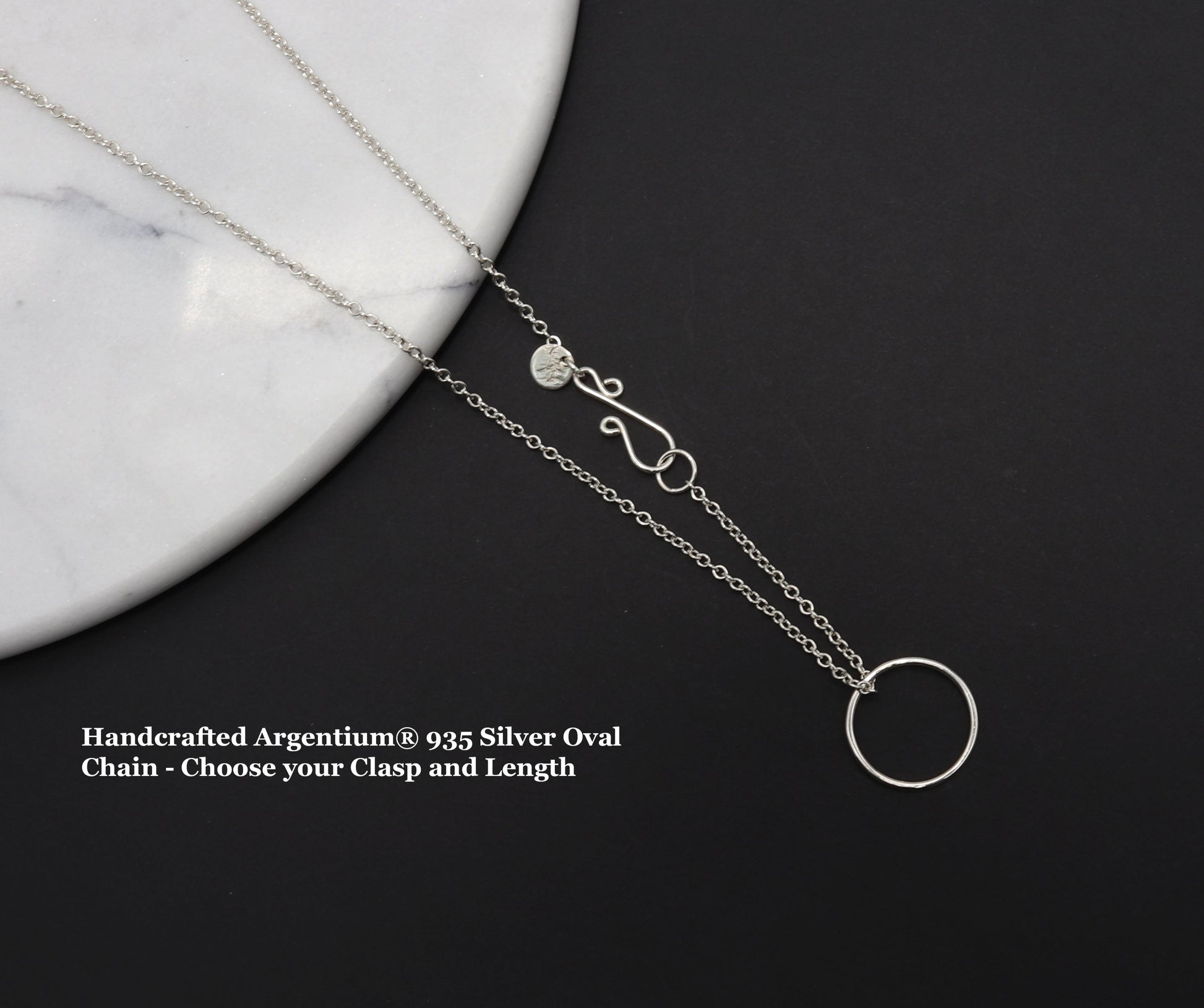 This handcrafted Open Circle Necklace shown on black background against white marble, is created using 100% recycled Argentium® 935 silver—brighter than traditional sterling, hypoallergenic, and tarnish-resistant by nature.