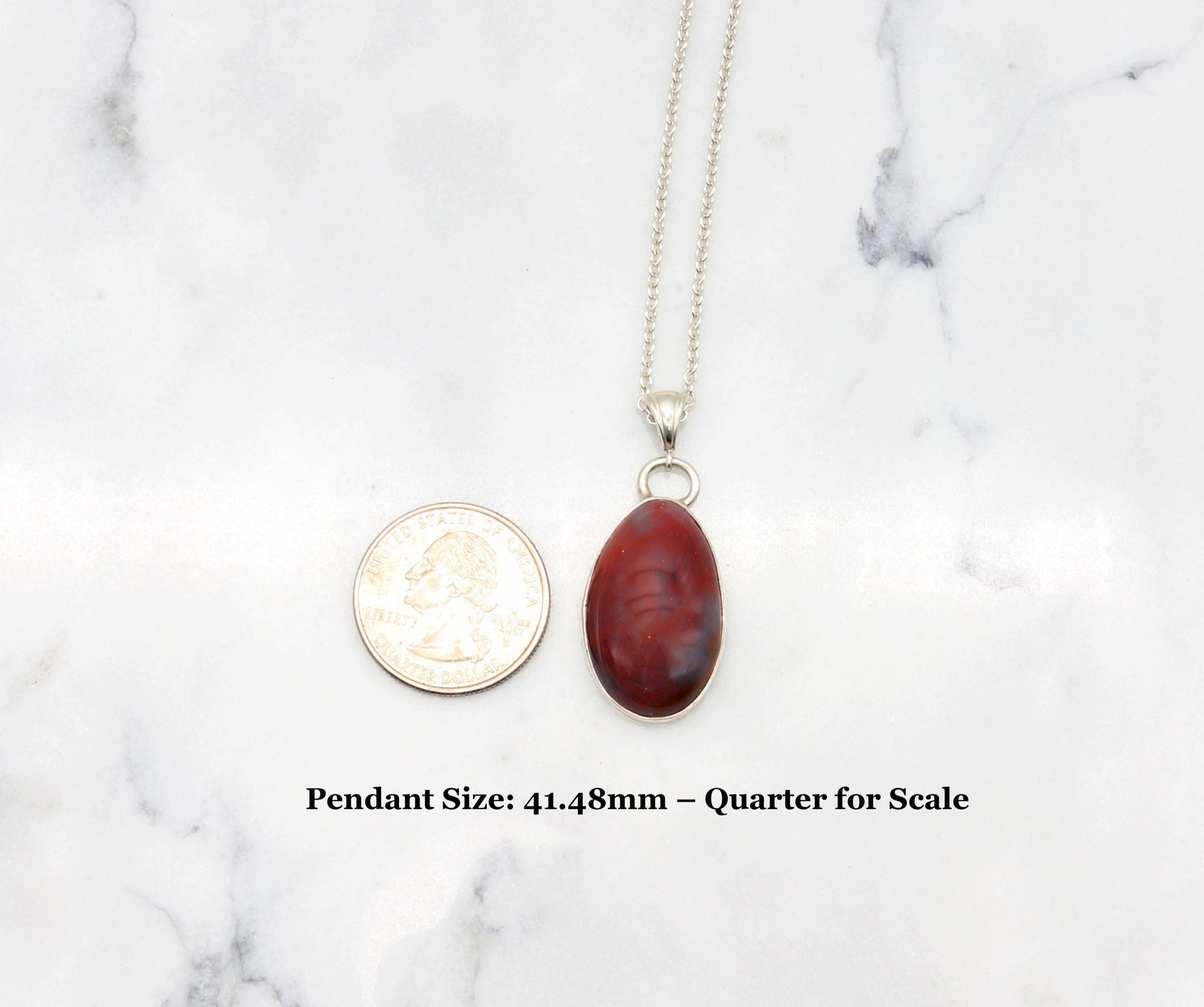 Arizona Petrified Rainbow Wood pendant, 41.48mm, laid flat next to a U.S. quarter for size perspective on white marble background.
