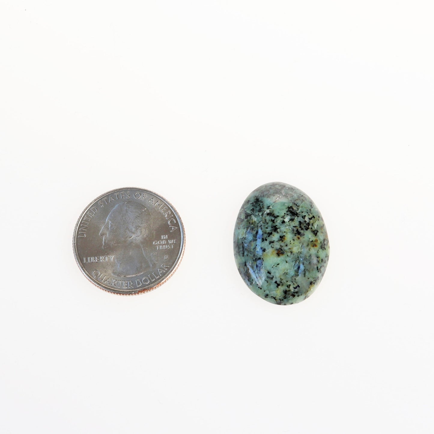 A 27mm × 20.15mm × 6.12mm oval Fraser River Turquoise gemstone with blue-green hues contrasted with a bold black matrix shown next to U.S. quarter for scale.