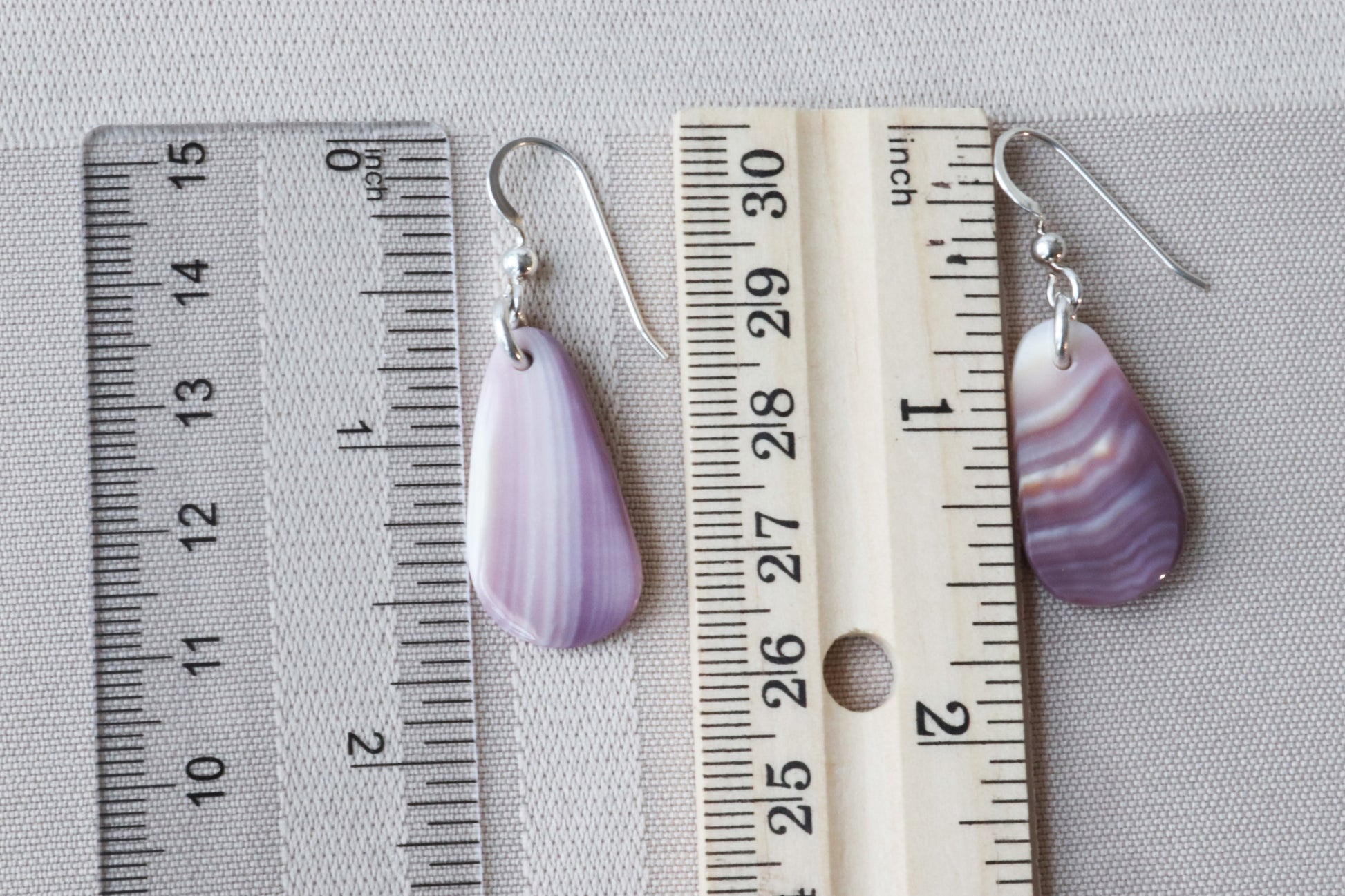 Earrings next to rulers to illustrate size perspective.
