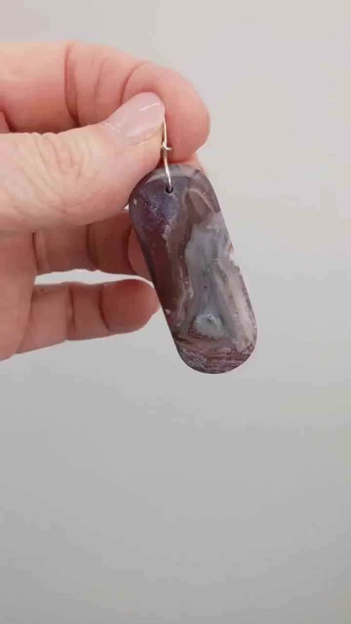 A video demo of the design and features of the Red Mexico agate with a human hand displaying the pendant.