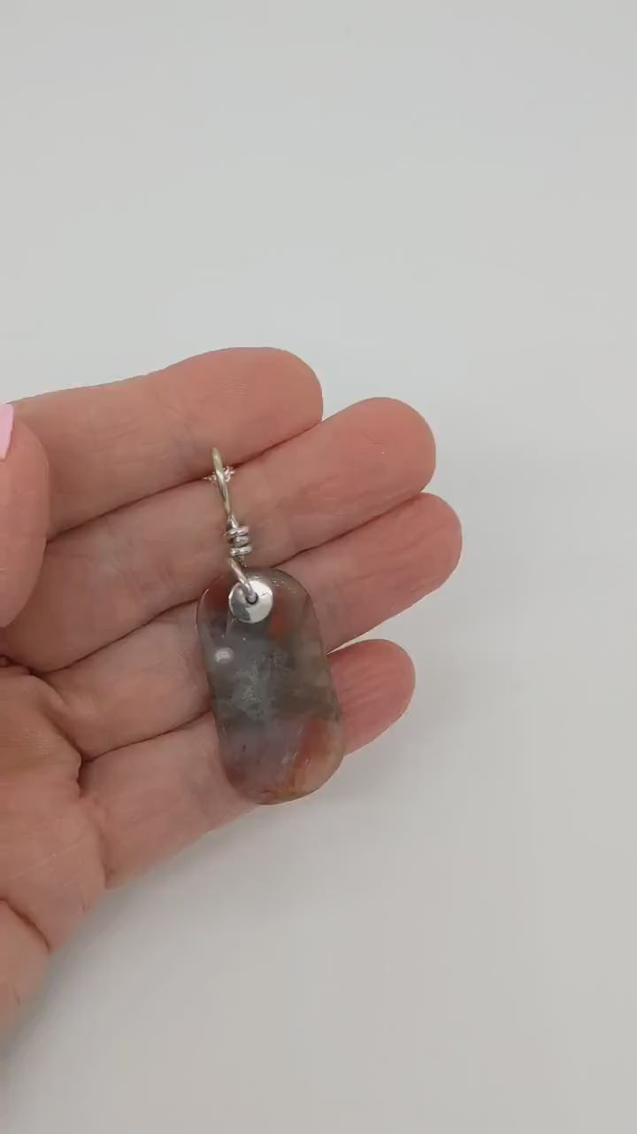 Demo video clip of  this one-of-a-kind pendant features a stunning tag-shaped cabochon of Petrified Rainbow Wood, hand-cut and polished to reveal warm hues of red, mauve, white, and translucent veining.  A custom crafted bail in Argentium Silver paired with complementary Argentium Chain.