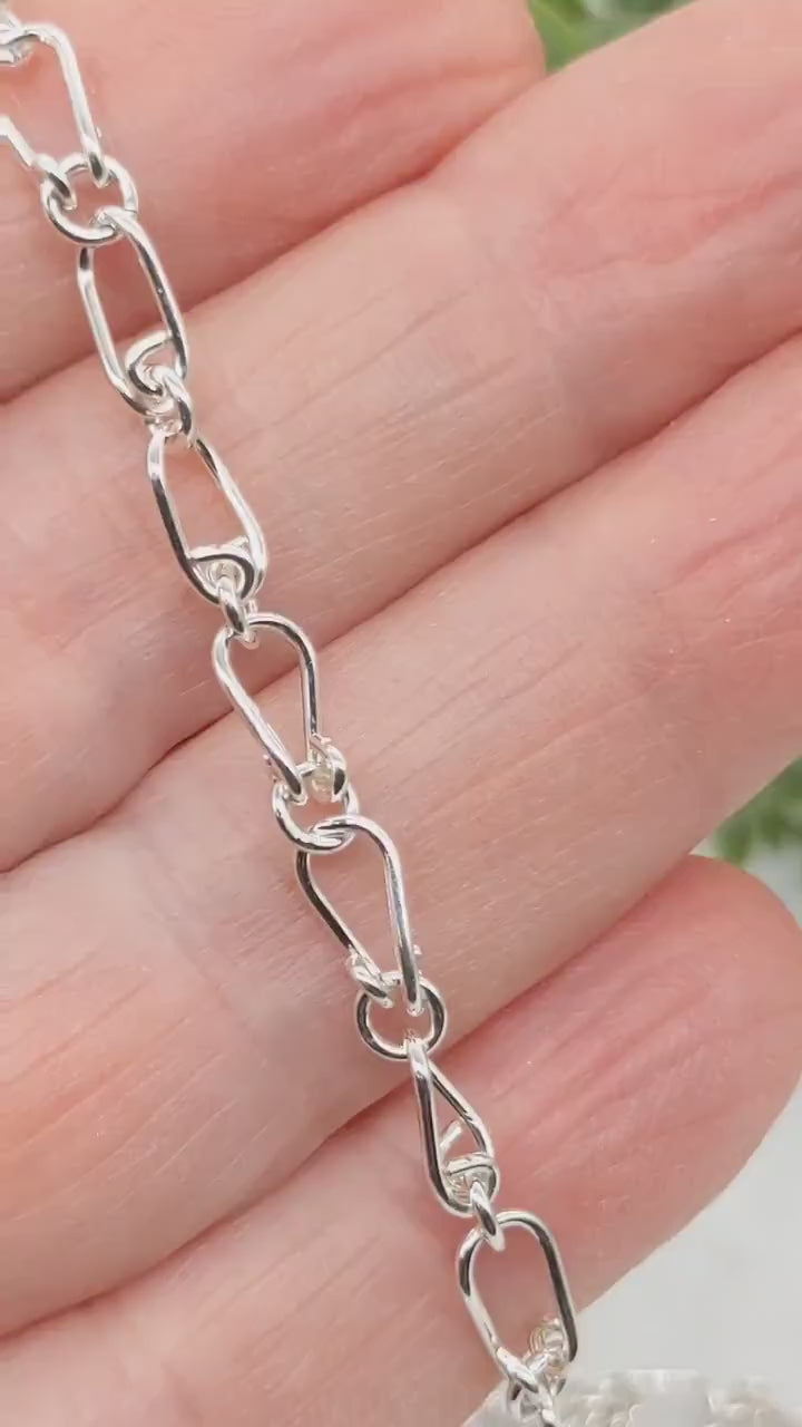 A demo in the hand of a human showing a closeup of the design of the handmade teardrop necklace chain.