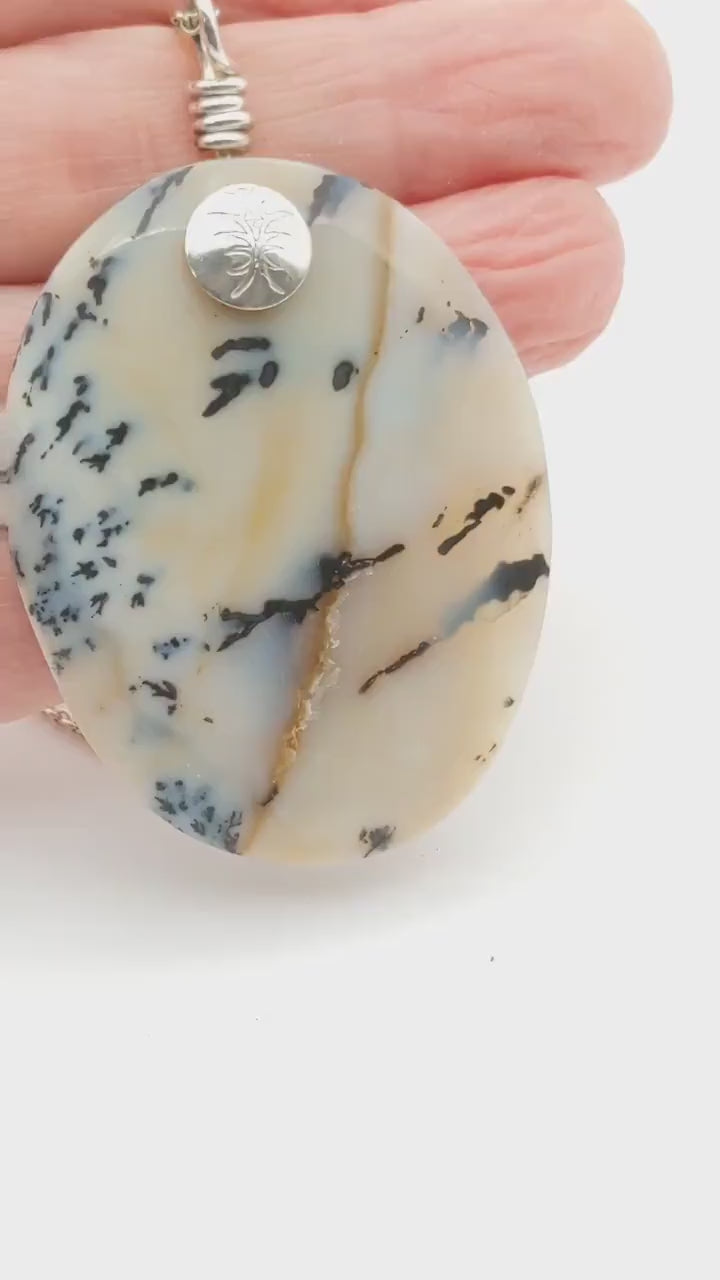 A video demo of a dendritic agate with a hand displaying the features of this pendant.