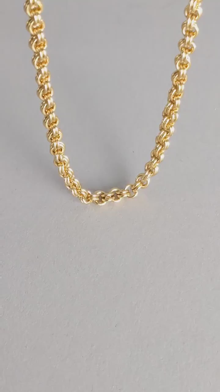 Hand showing the double cable link brass necklace to reveal its design.