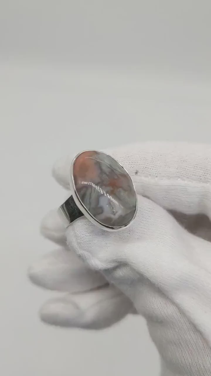 A video demo of a handmade Crazy Lace Agate ring set in Argentium Silver sized 7.75 u.s. A human hand is displaying the features of the ring.