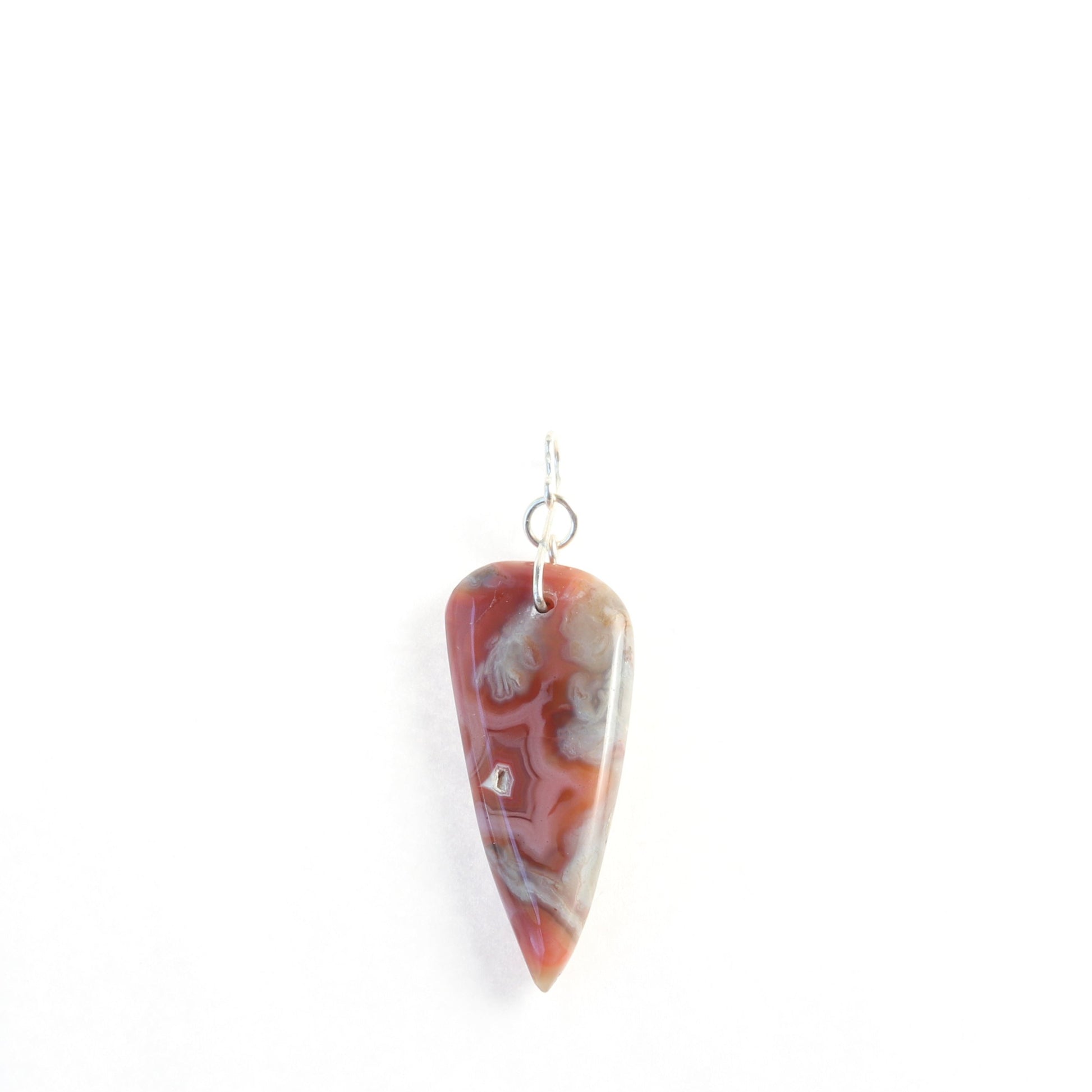 Polished on both sides is this arrowhead shaped Crazy Lace Agate arrow shaped gemstone pendant. 
Unique swirling patterns and vibrant mauve deep reds and gray hues feature a small natural crystal inclusion.  The pendant is styled with a figure-8 Argentium wire bail.