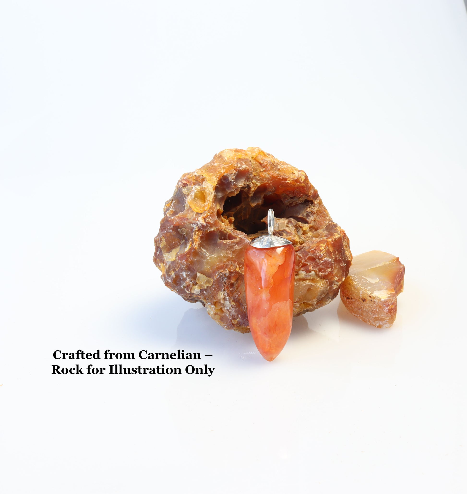 Handcrafted Carnelian Agate pepper-shaped pendant with Argentium 935 Silver bail, 54.81mm, standing adjacent to a raw Carnelian rock (for illustration only, not for sale) on a light background